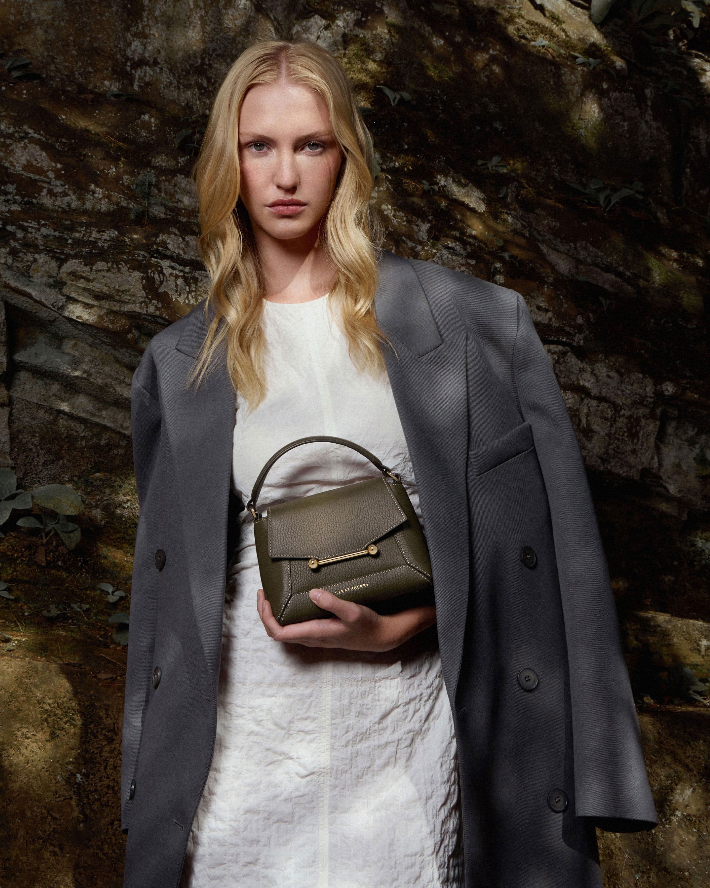 A woman in a white dress holding a green purse