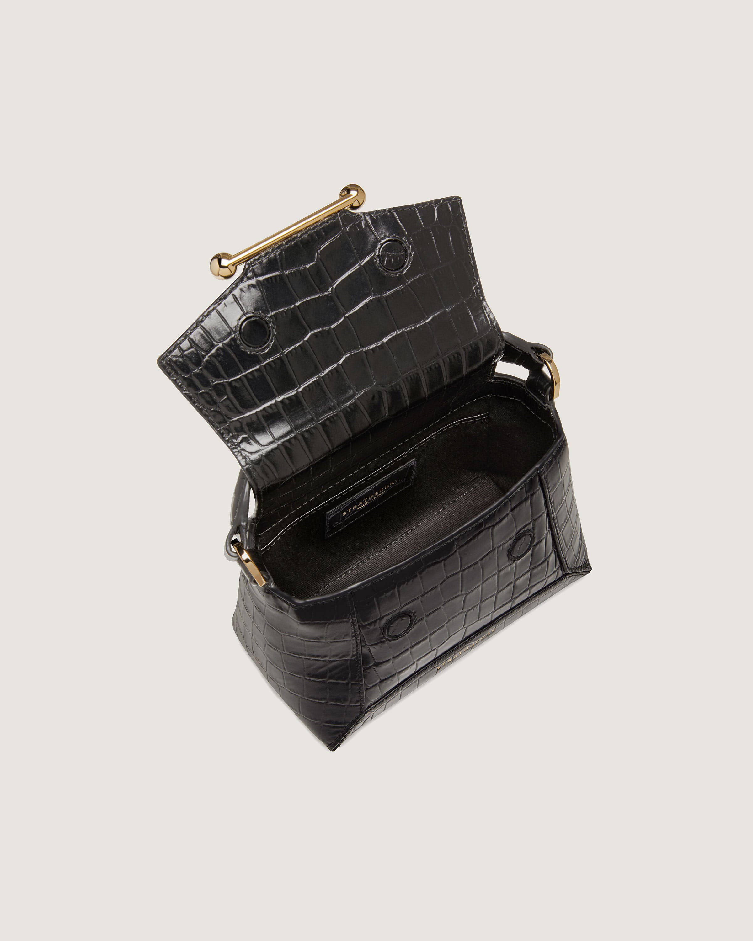 A black crocodile - embossed purse with a gold handle