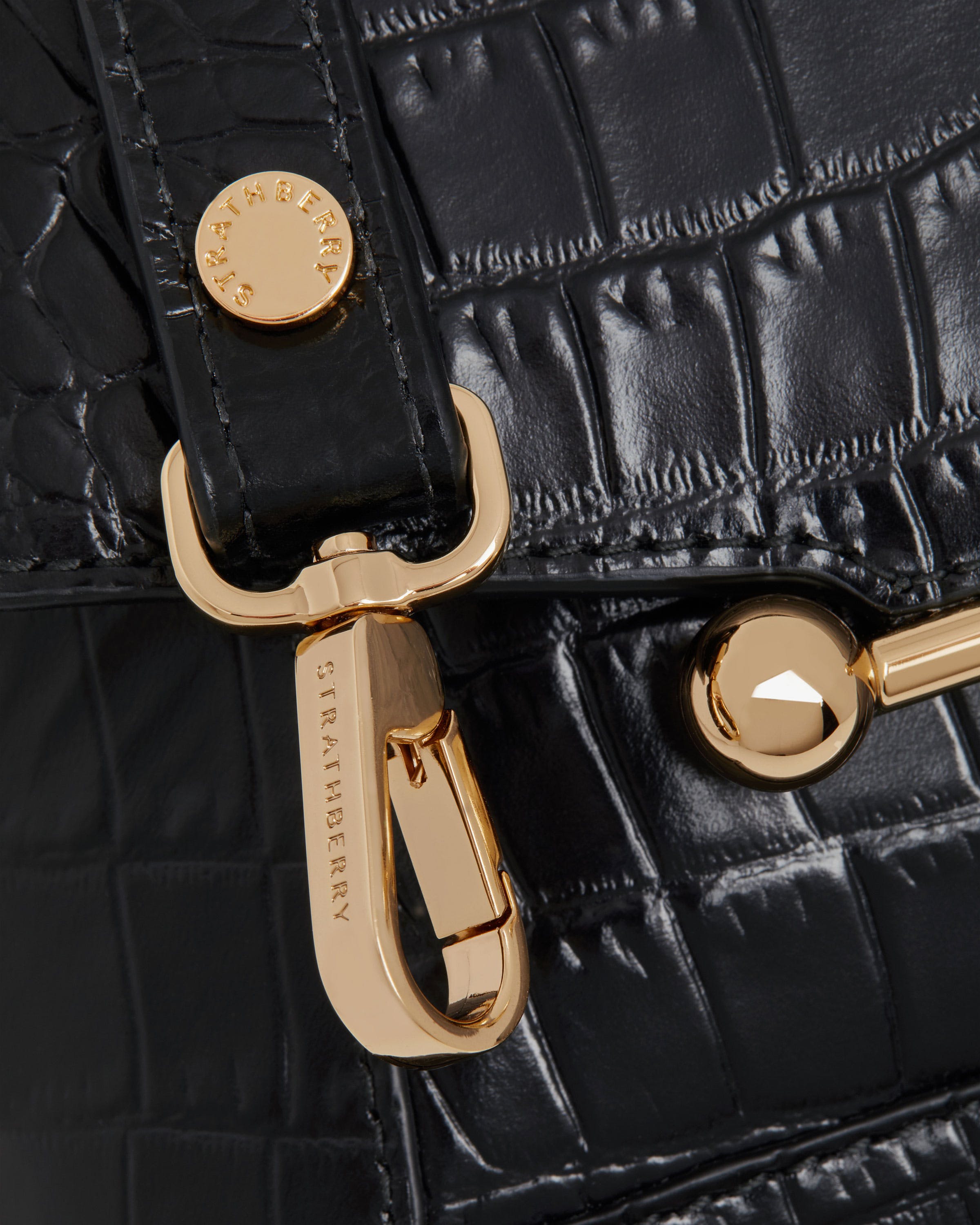 A close up of a black purse with a gold handle