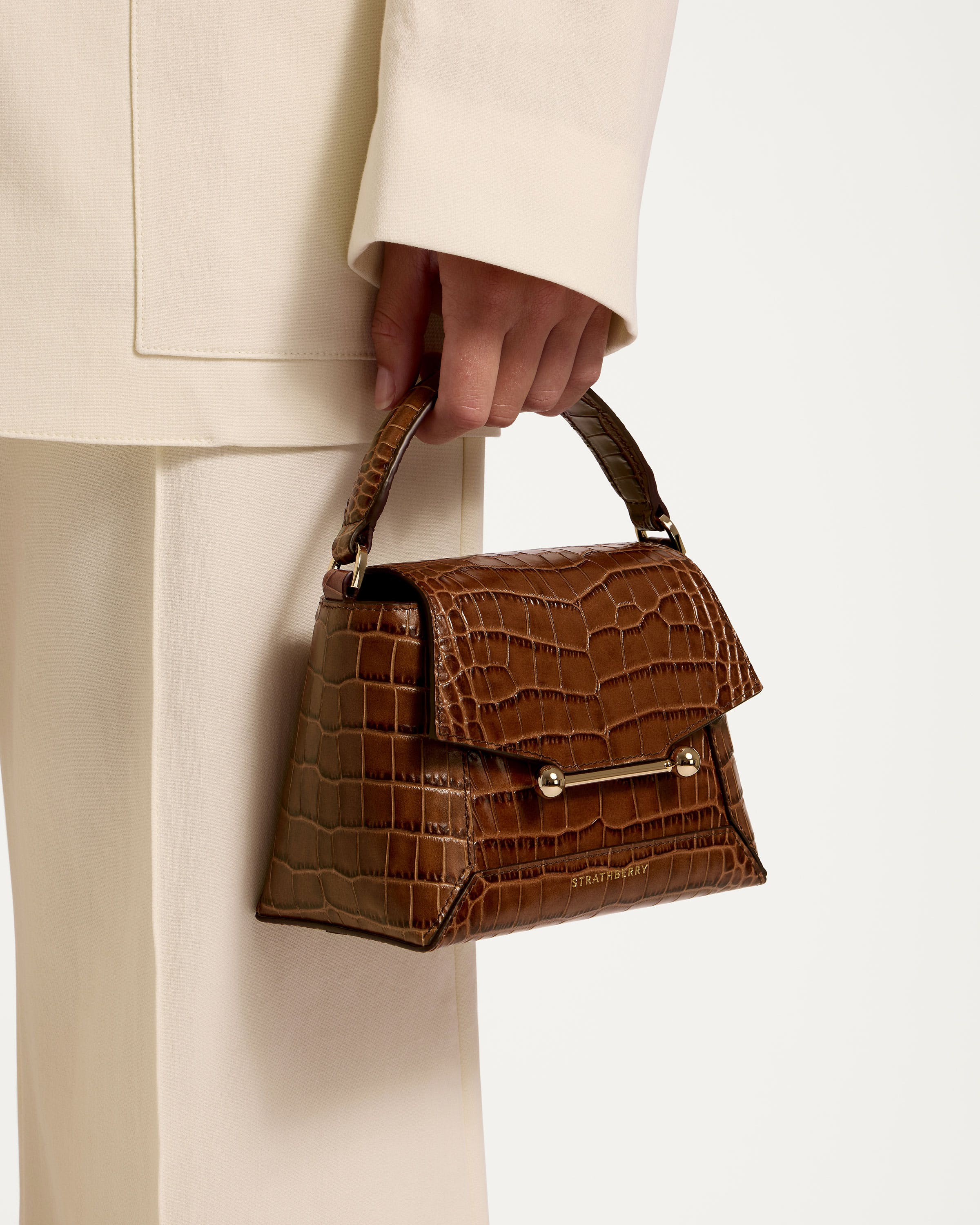 A person in a white suit holding a brown purse