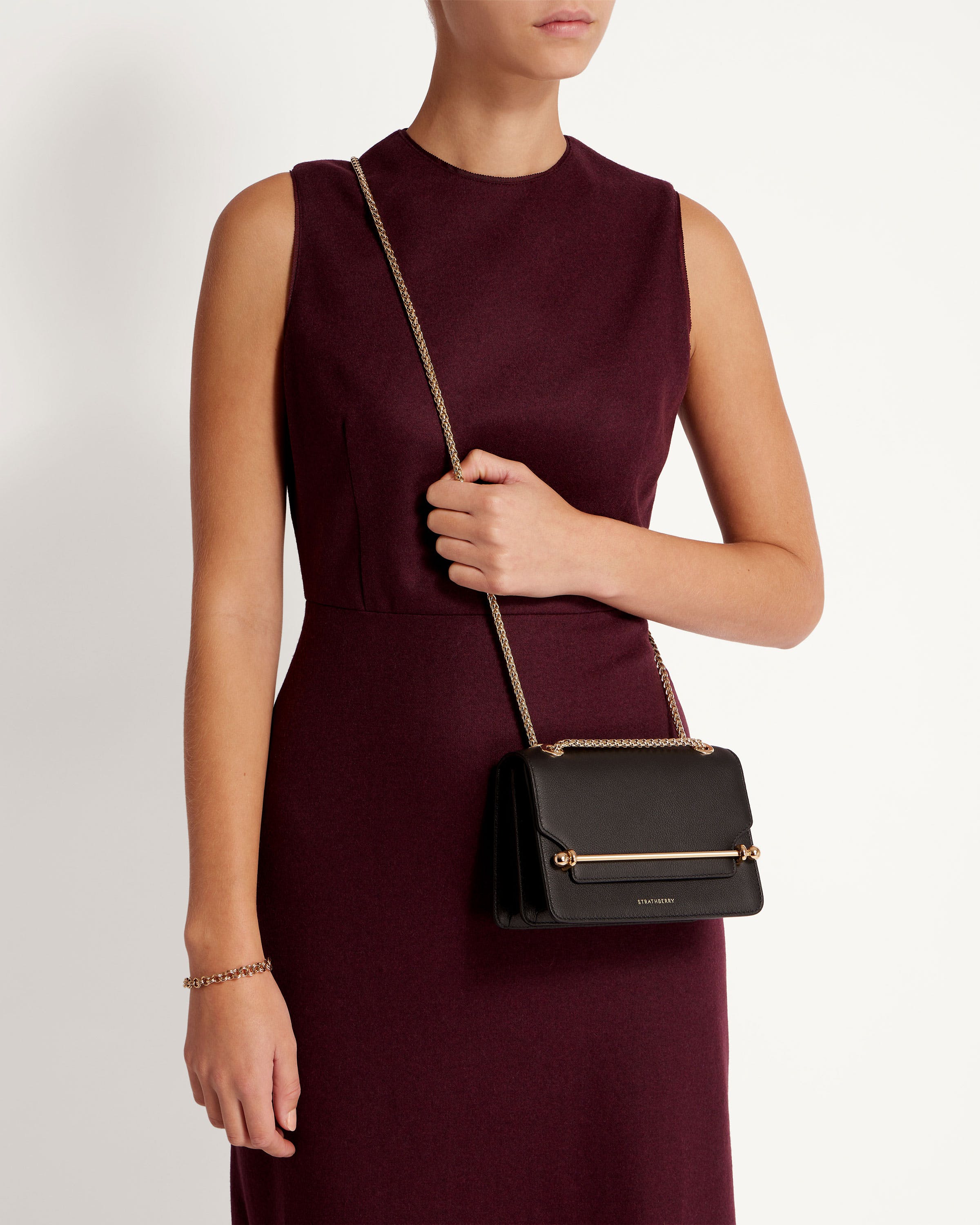 A woman in a maroon dress holding a black purse