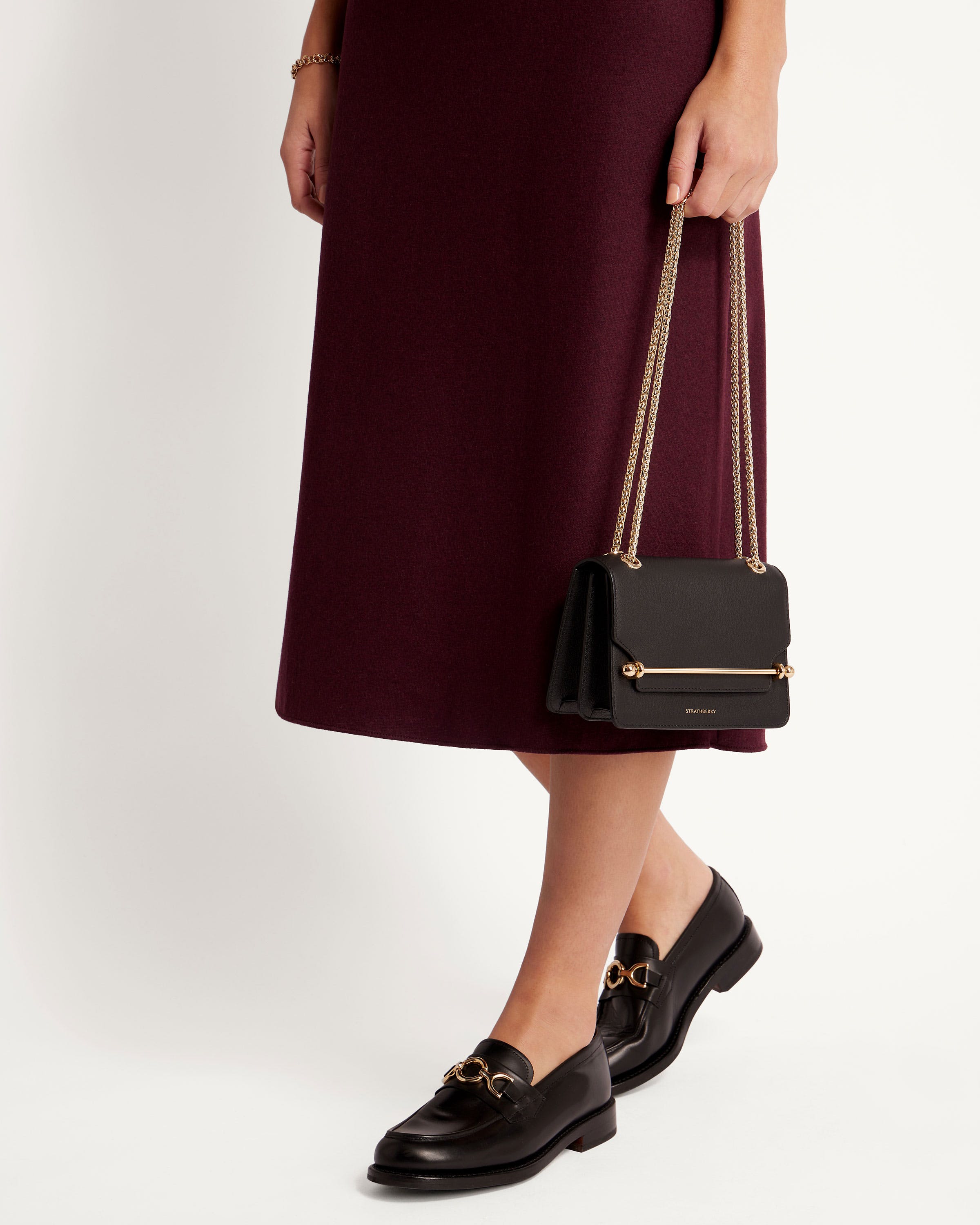 A woman in a maroon dress holding a black purse