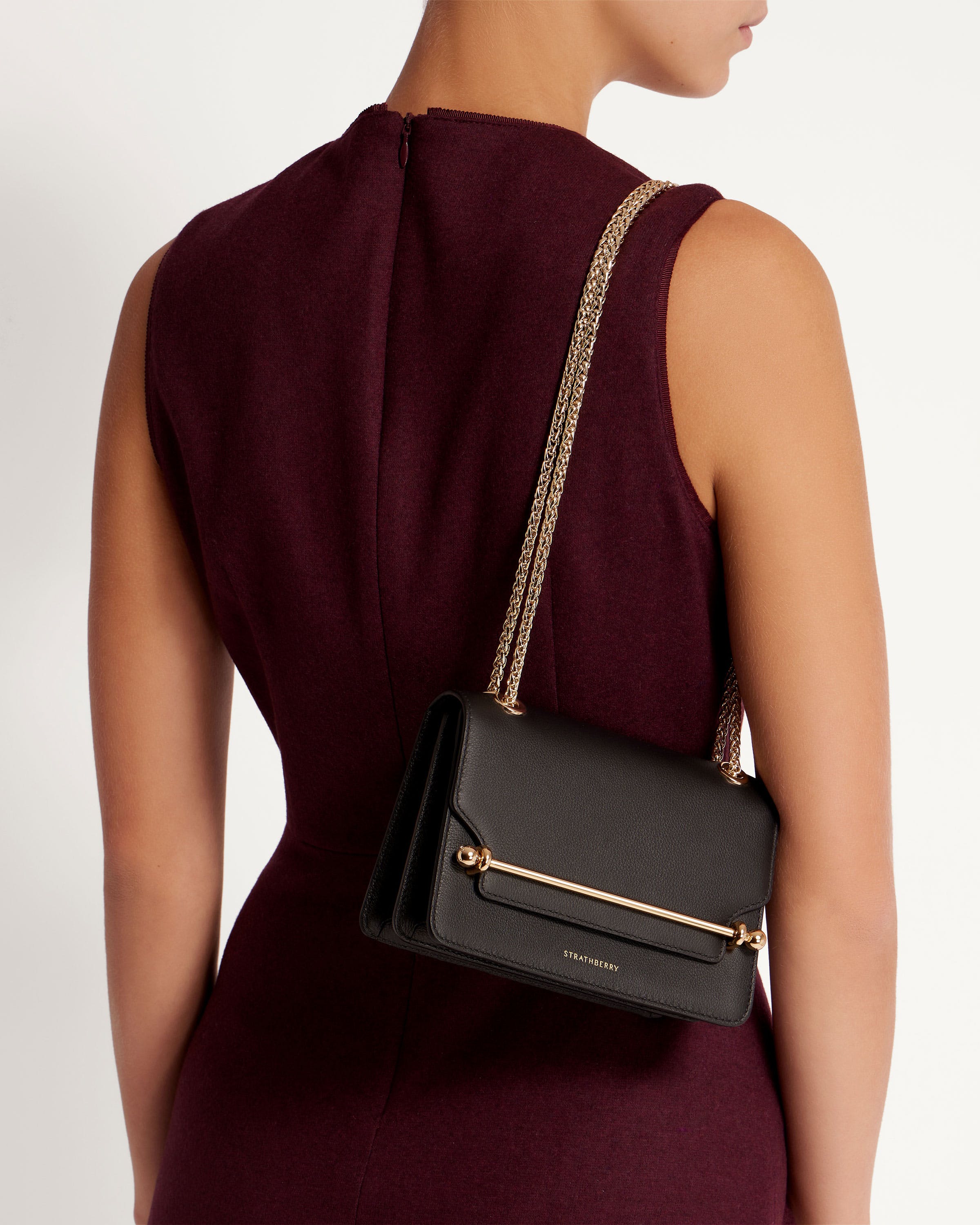 A woman in a maroon dress carrying a black purse