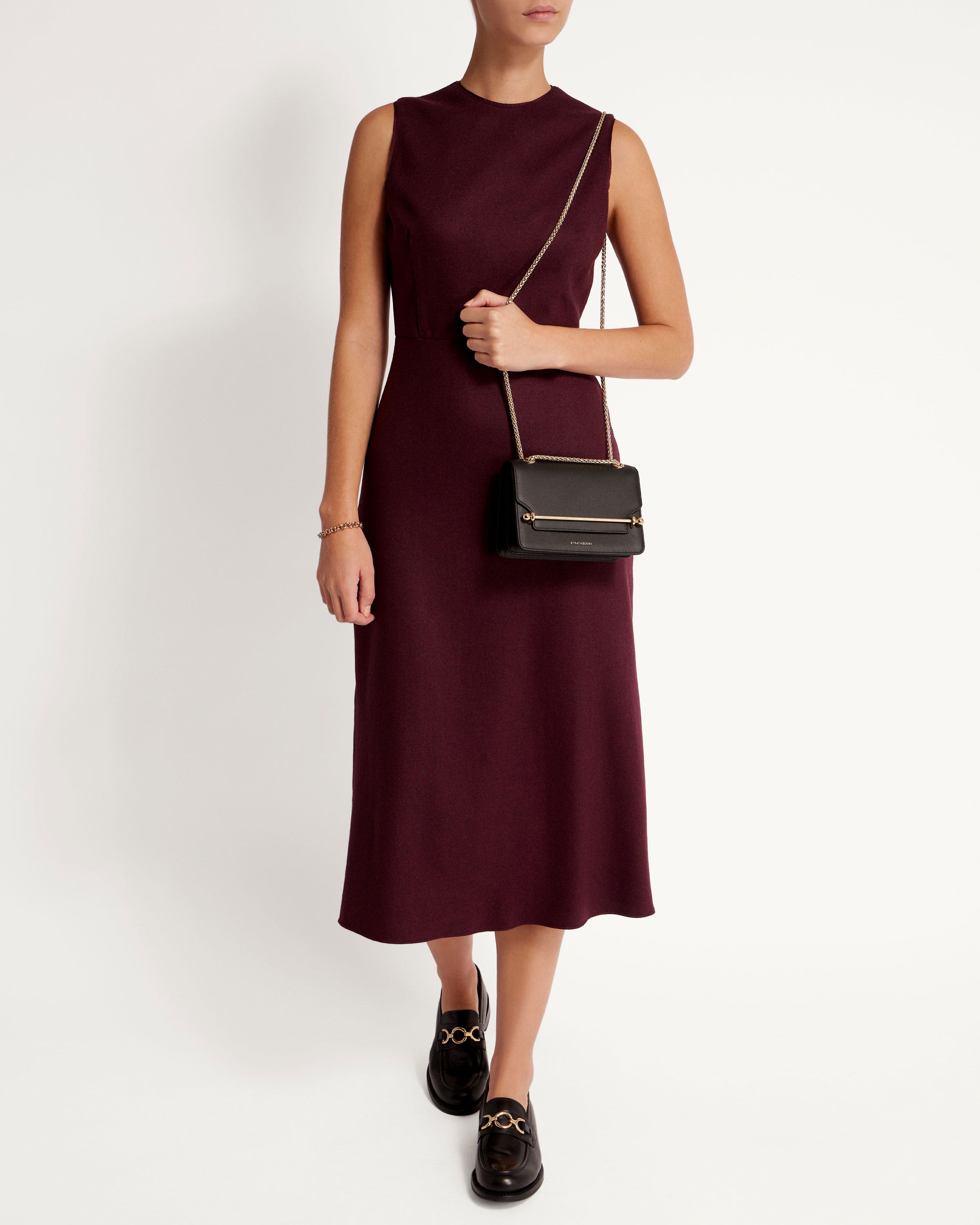 A woman in a maroon dress holding a black purse