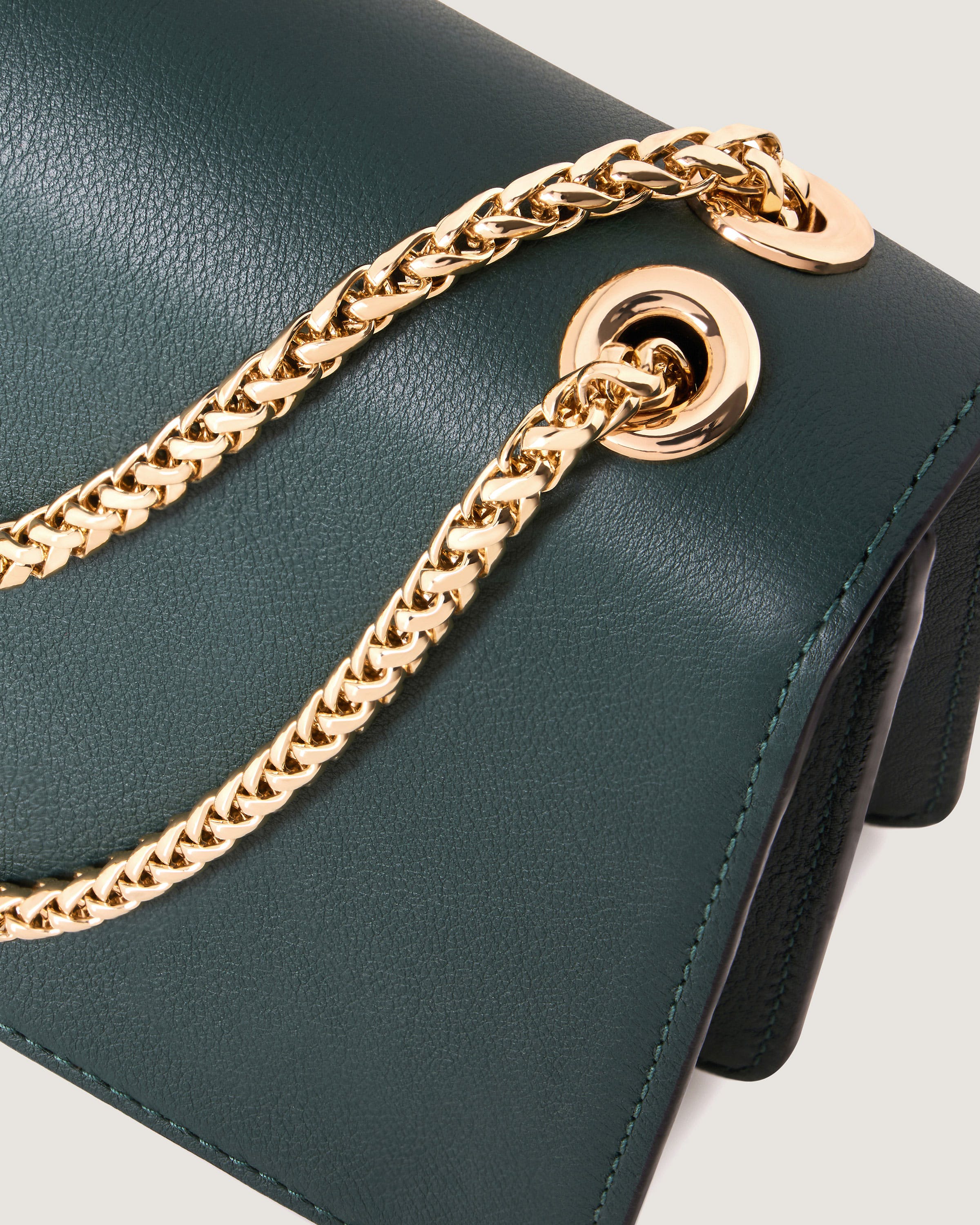 A close up of a green purse with a gold chain