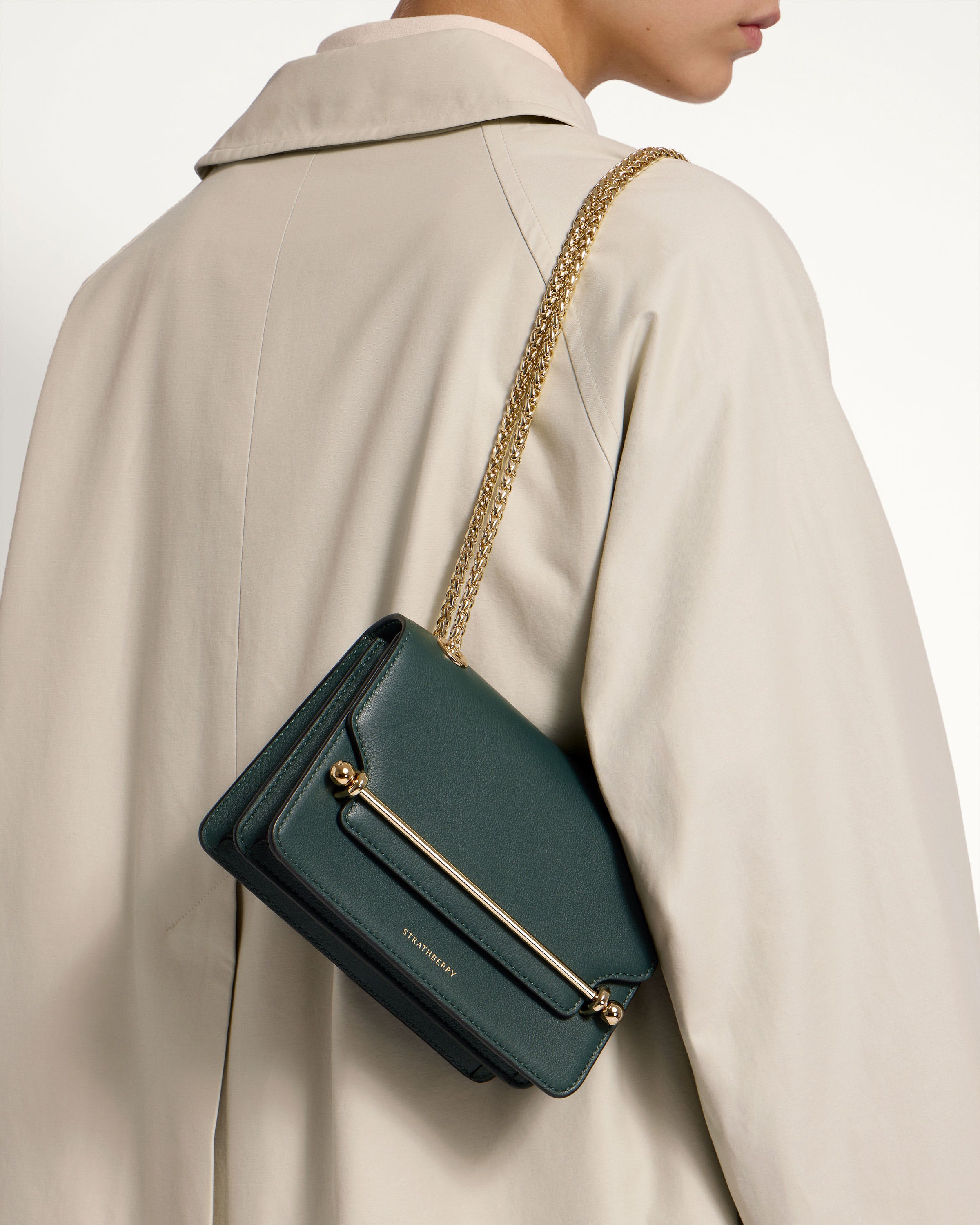 A woman is holding a green purse on her shoulder