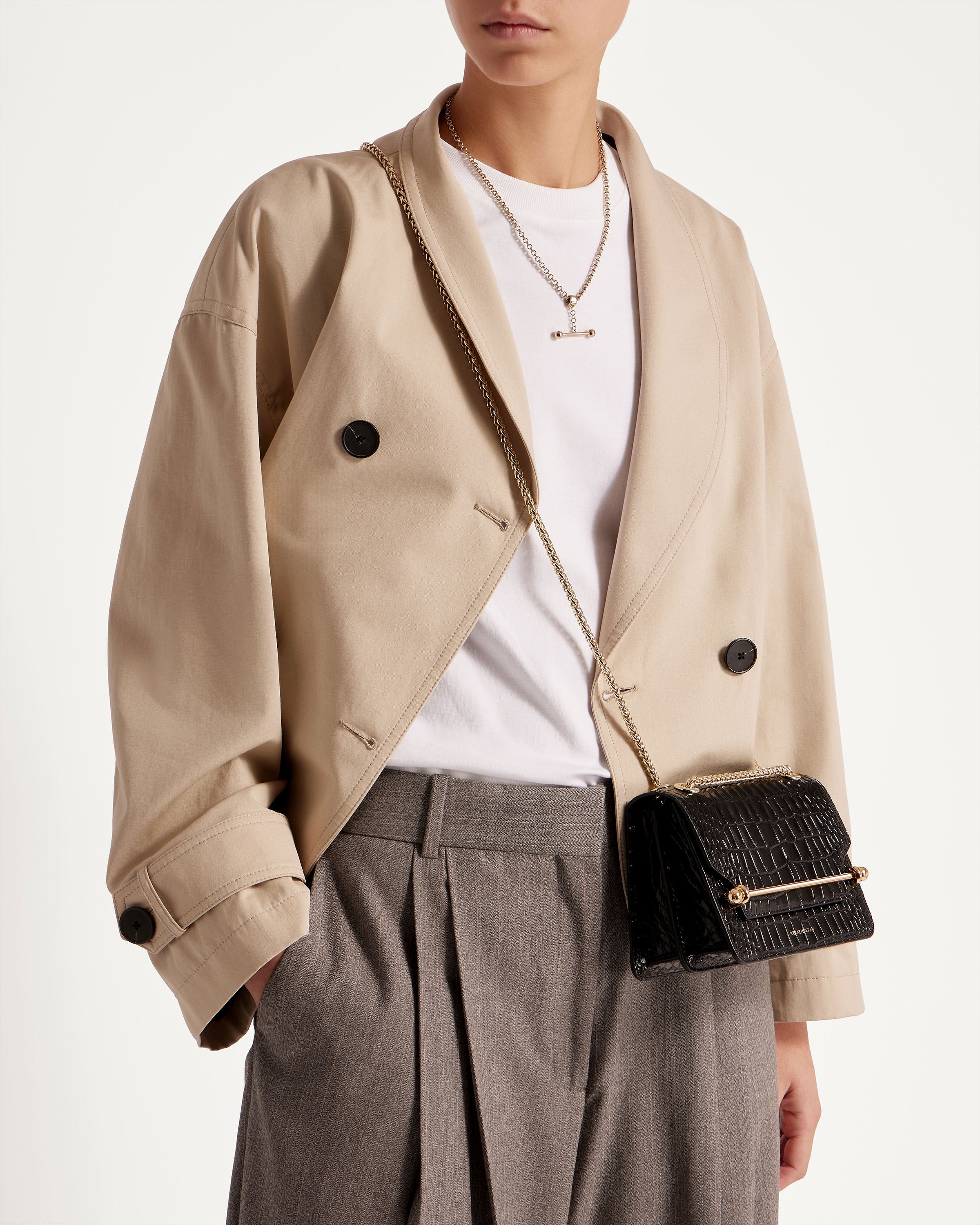 A woman wearing a beige jacket and a black purse