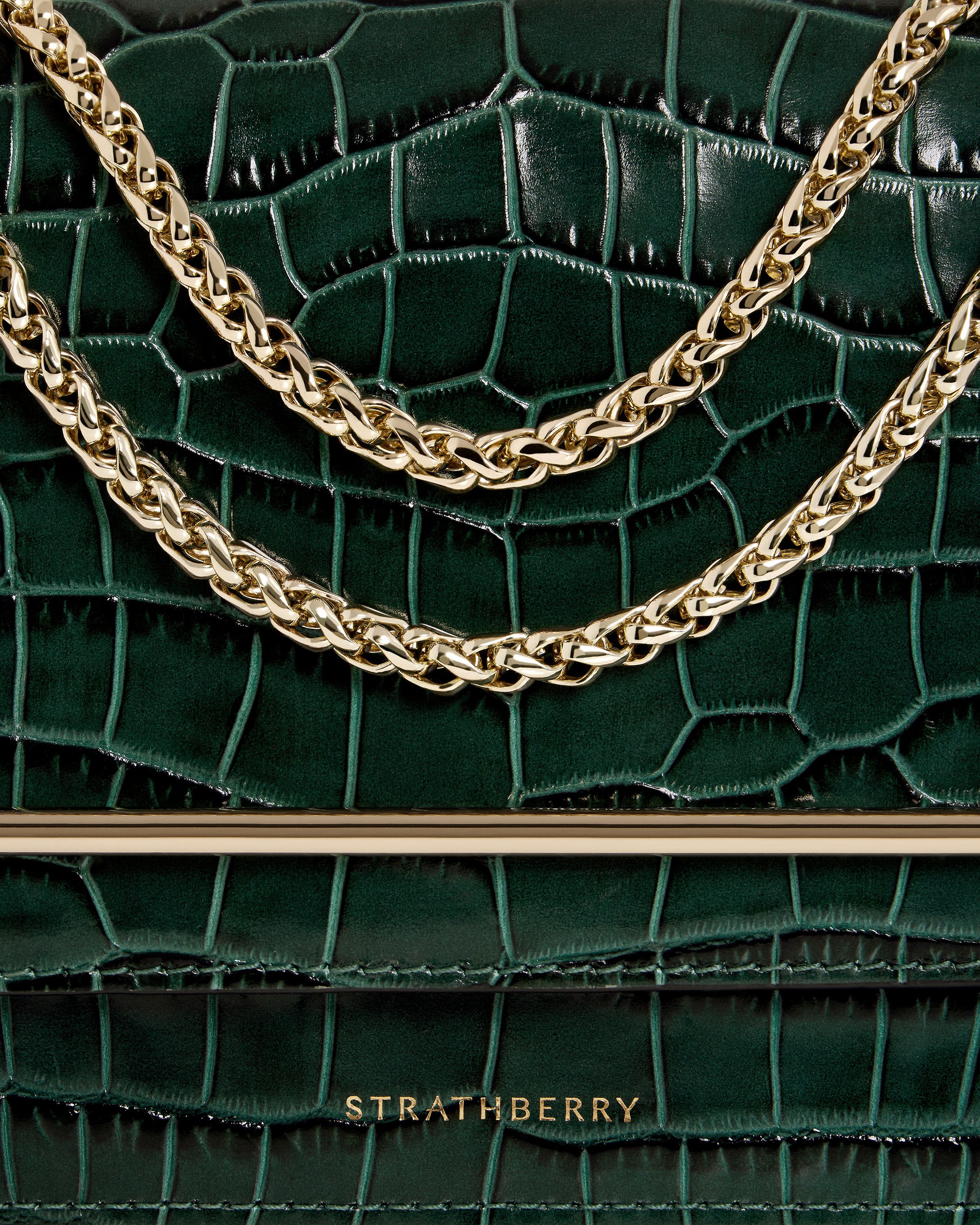 A green handbag with a gold chain hanging from it