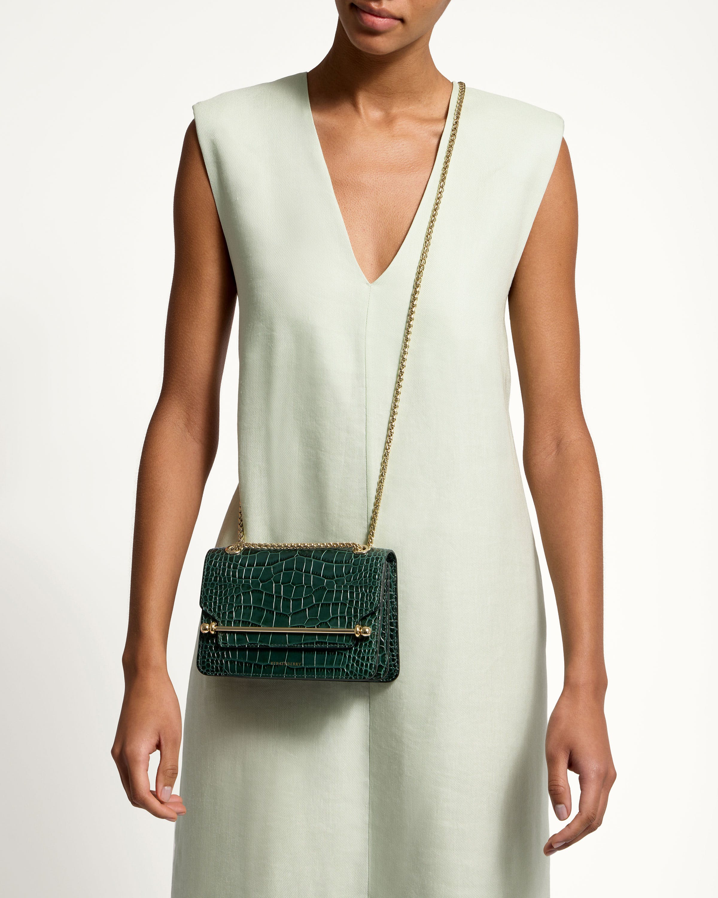 A woman in a white dress holding a green purse