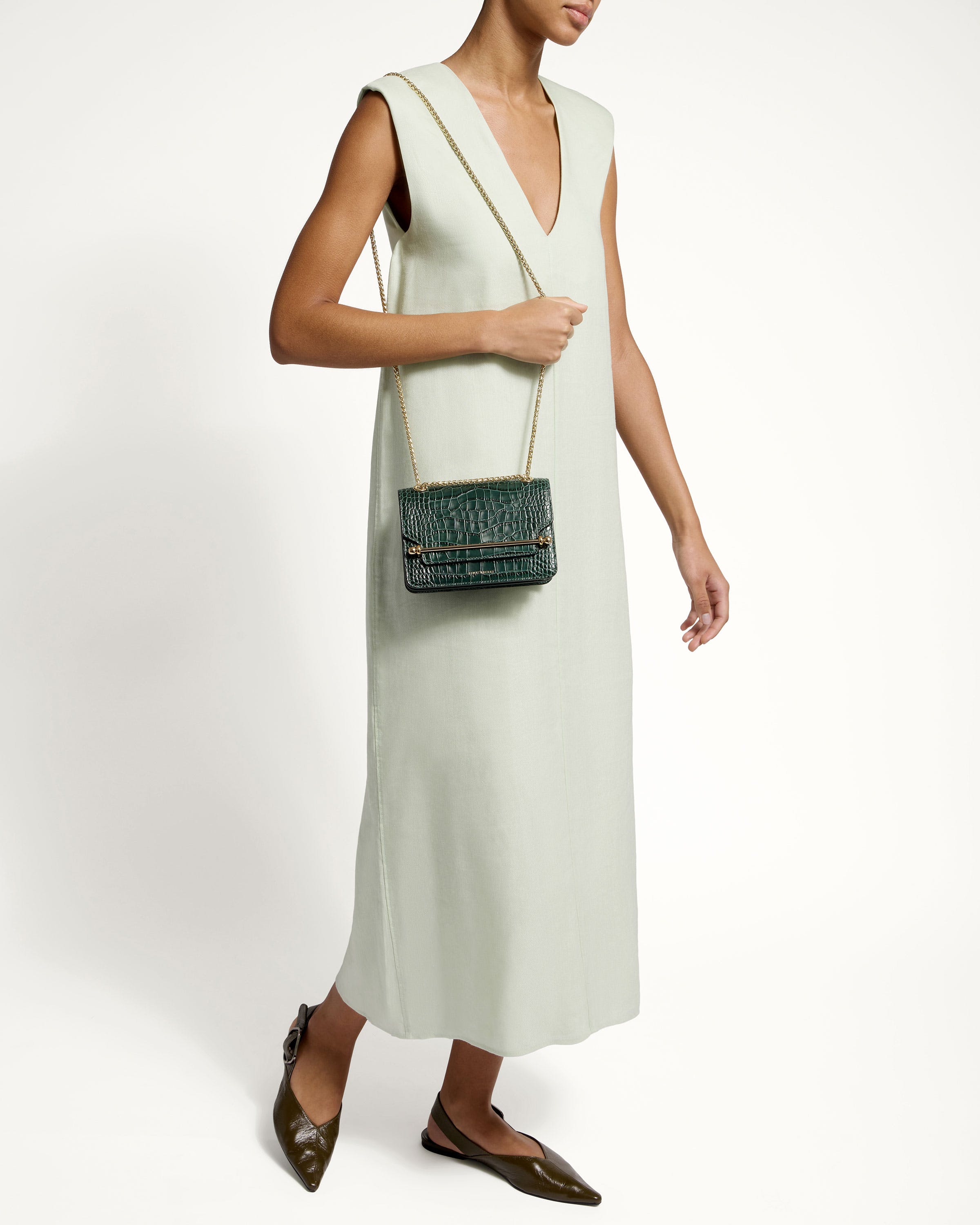 A woman in a white dress holding a green purse