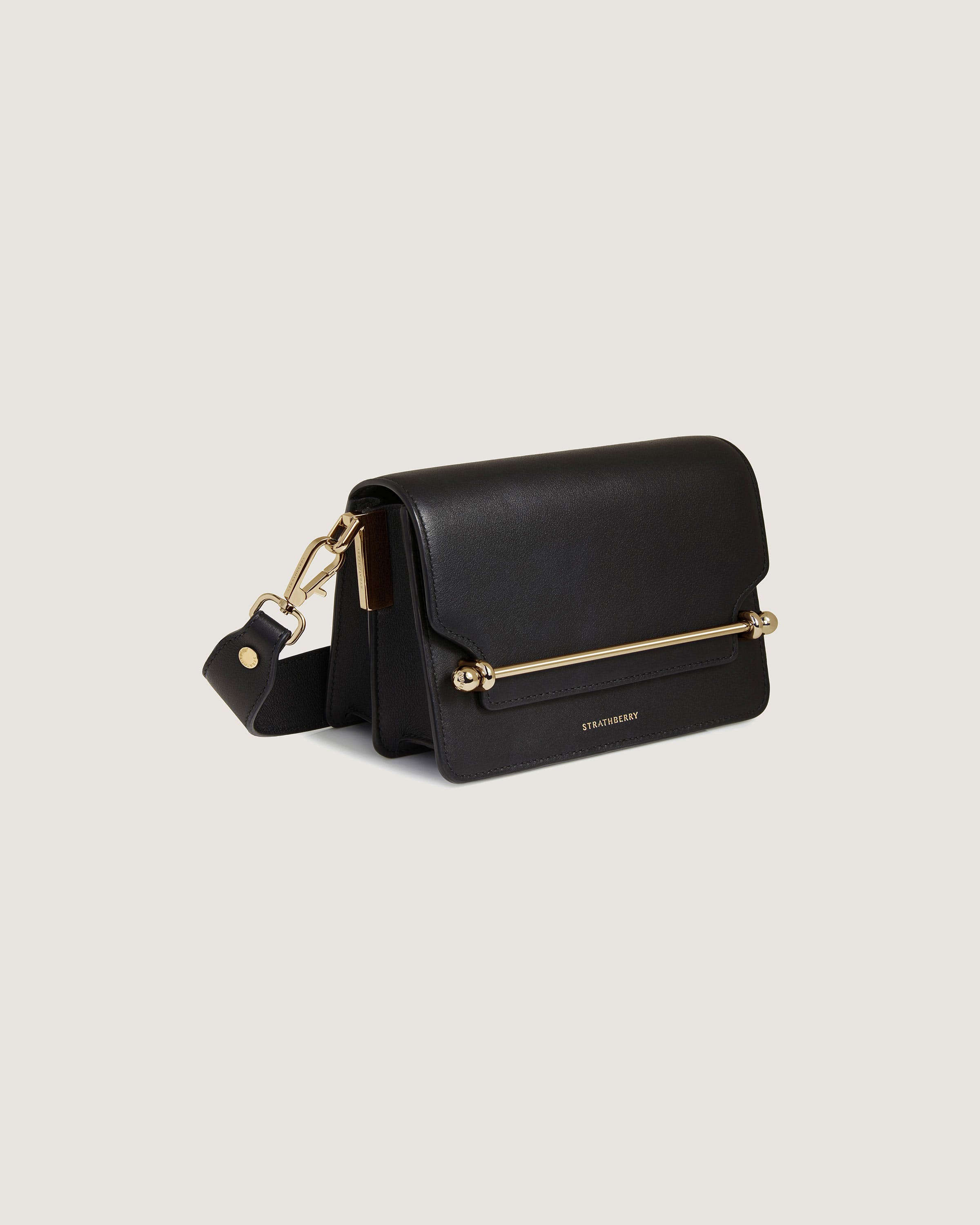 A black cross body bag with a gold handle