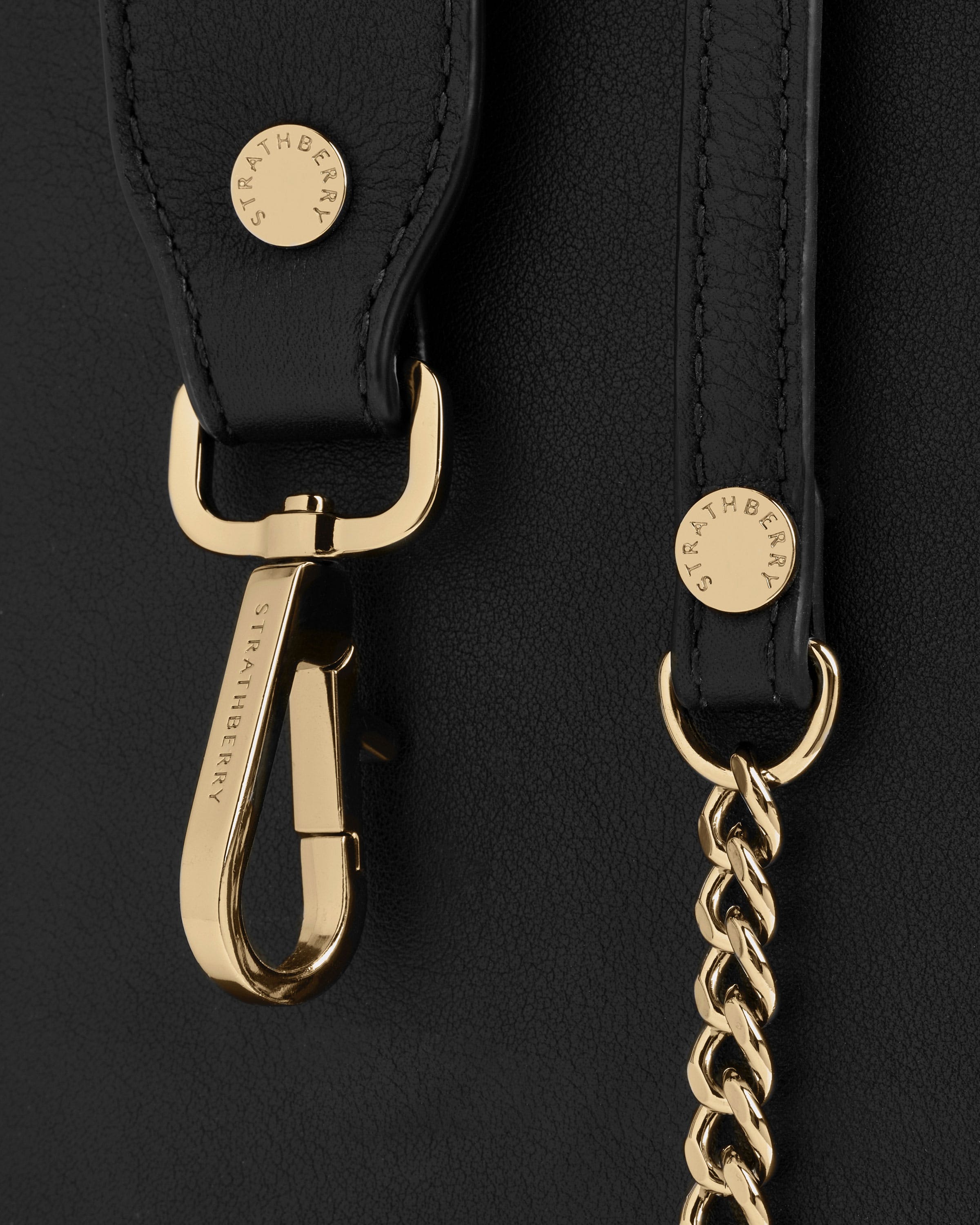 A close up of a black purse with a gold chain