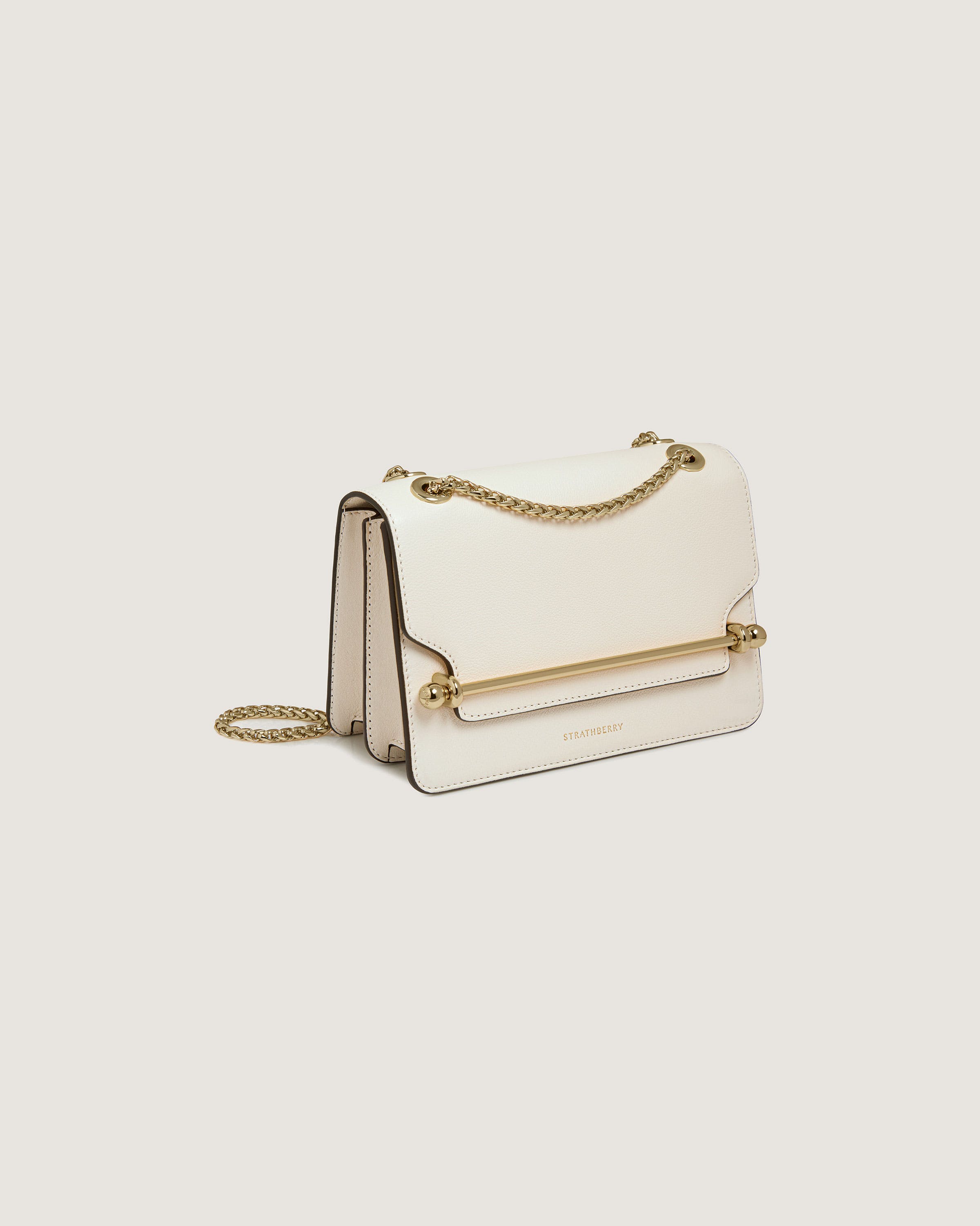 A white purse with a gold chain hanging from it