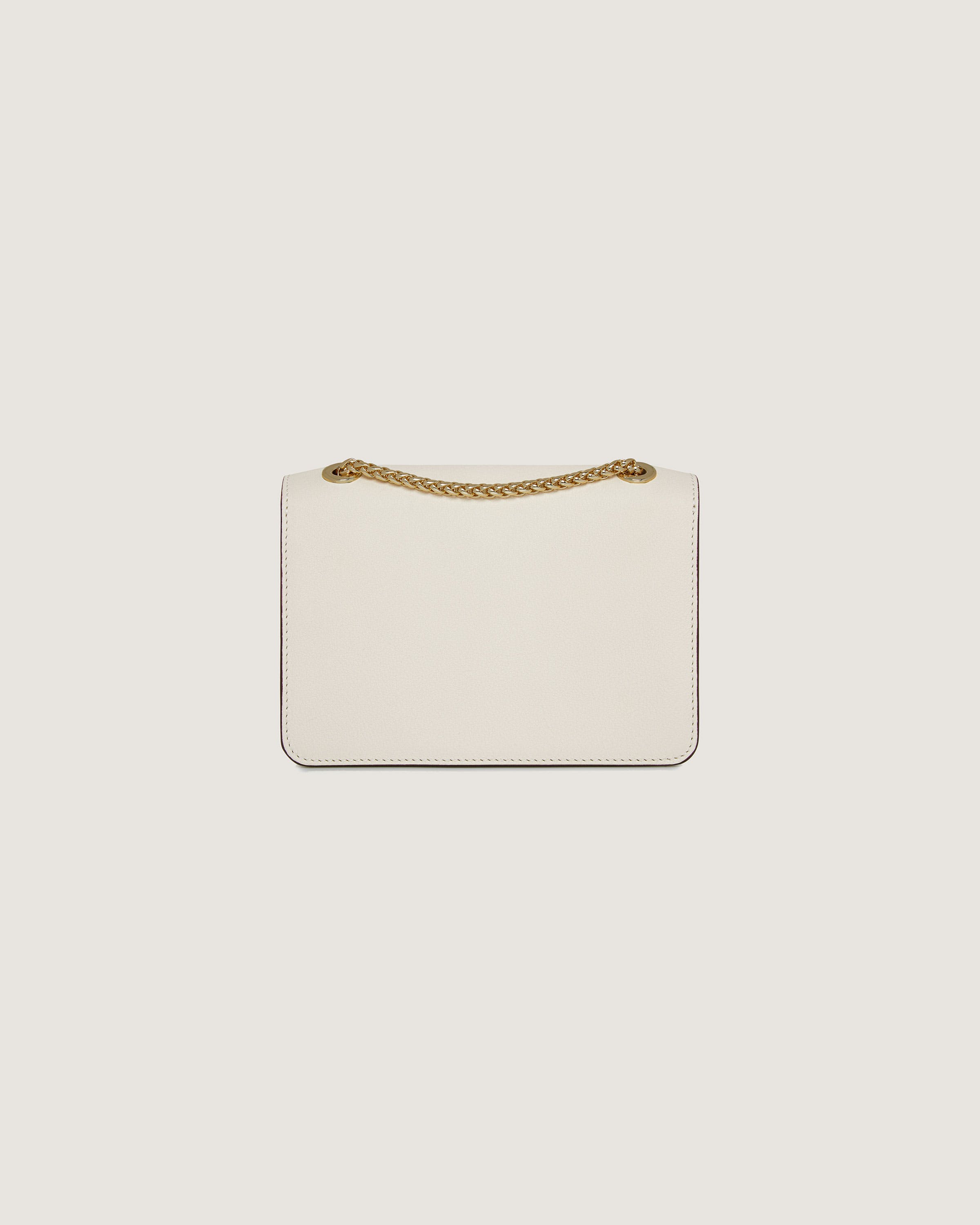 A white purse with a gold chain hanging from it