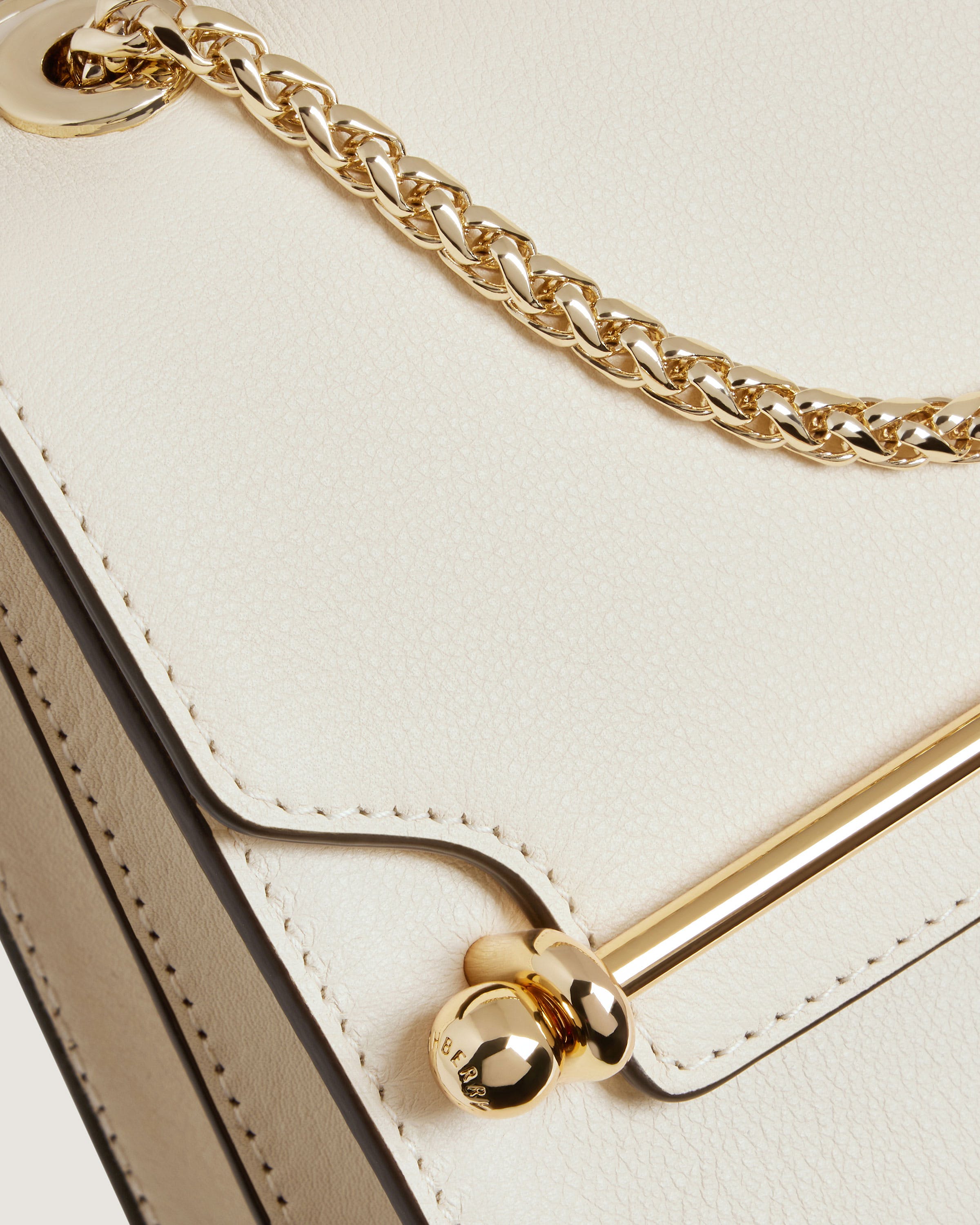 A white purse with a gold chain on it