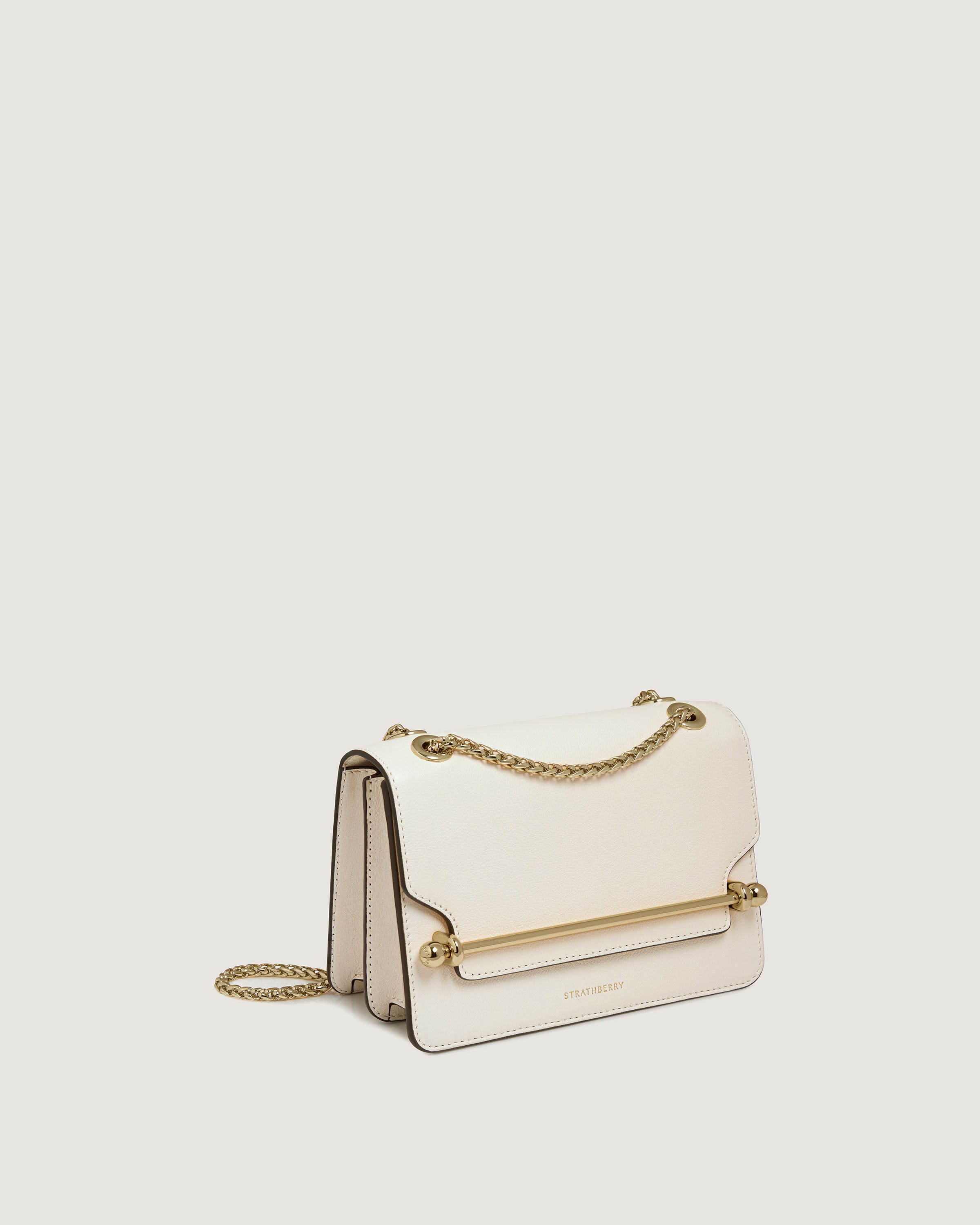 A white purse with a gold chain hanging from it