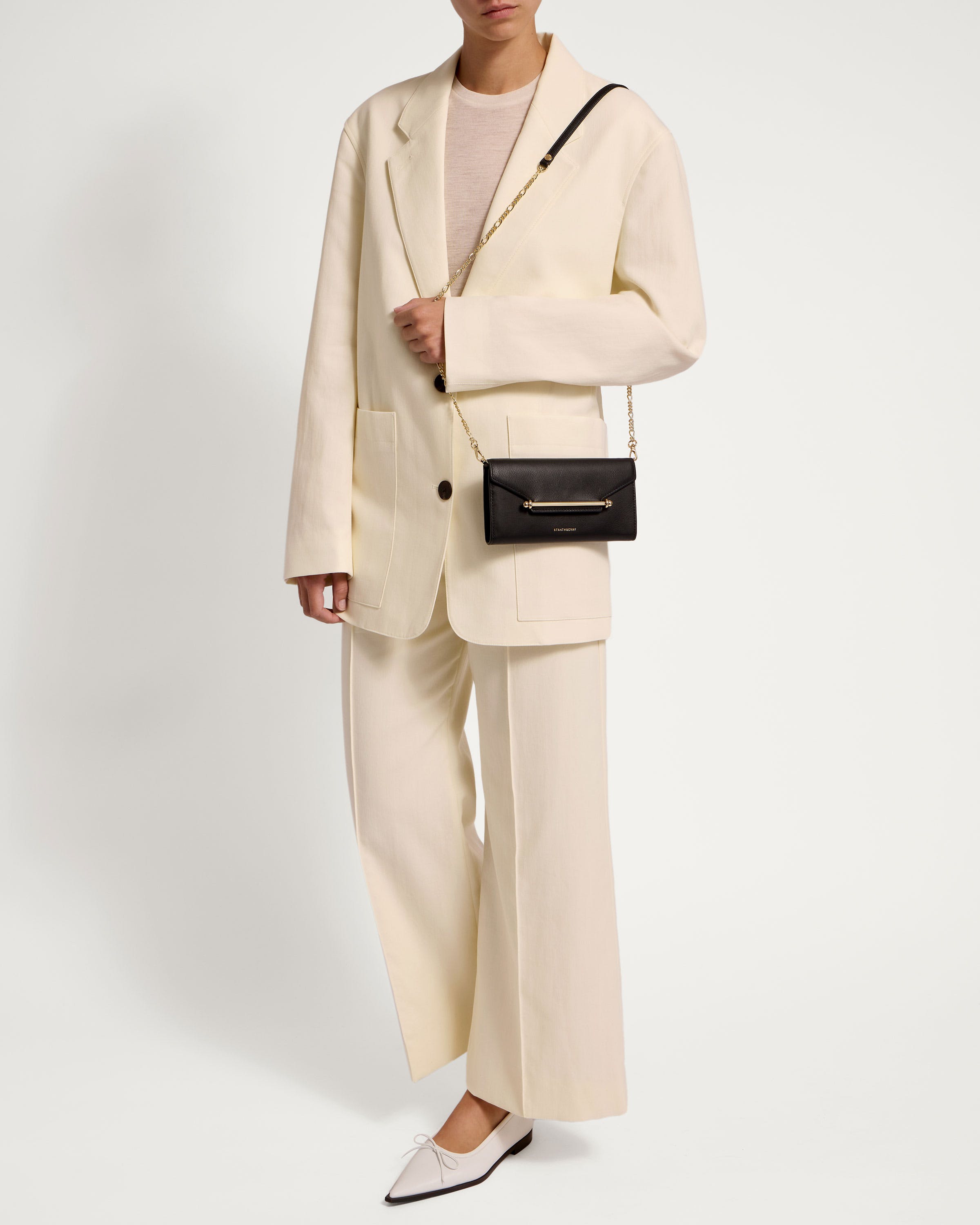 A woman wearing a white suit and black purse