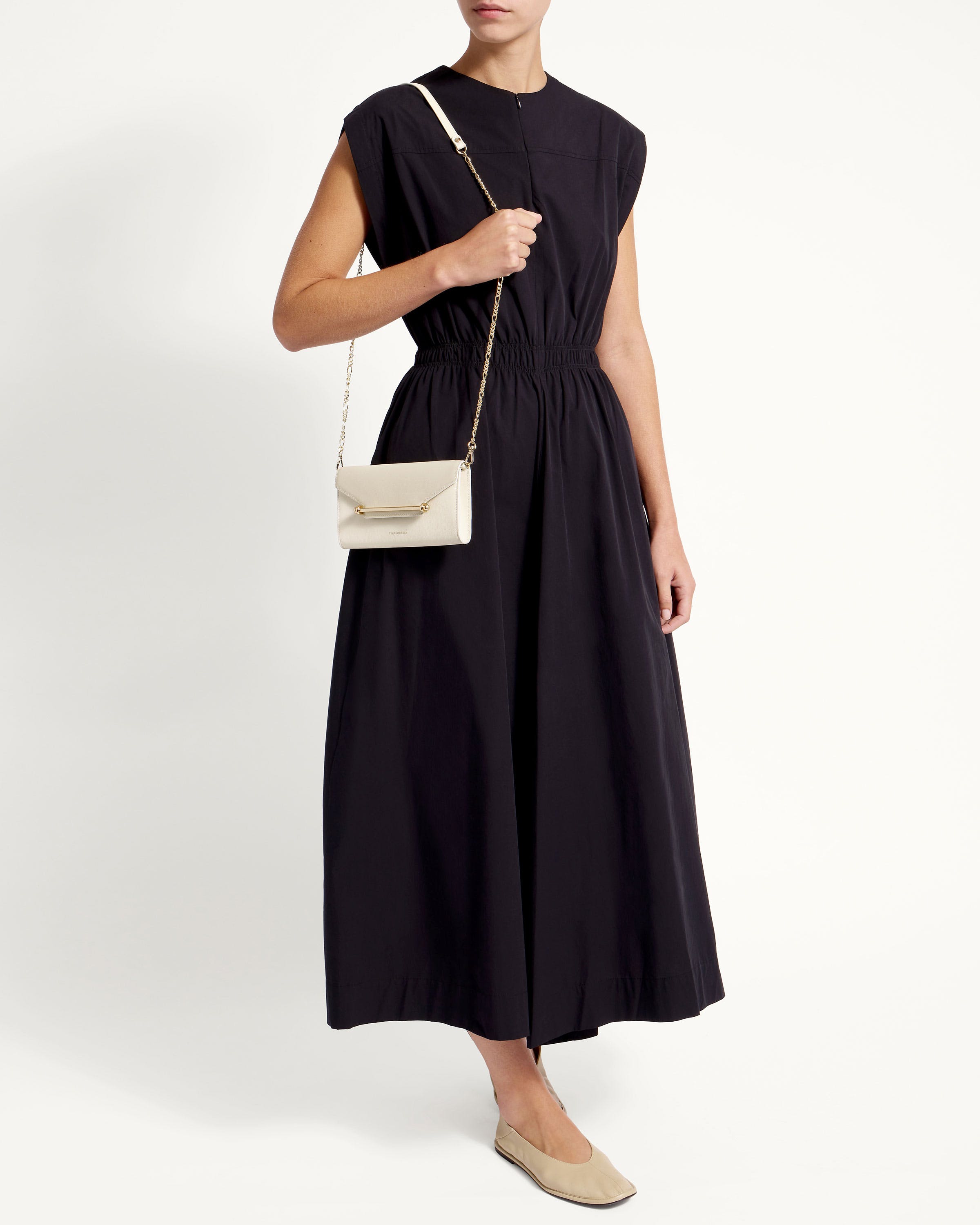 A woman in a black dress holding a white purse