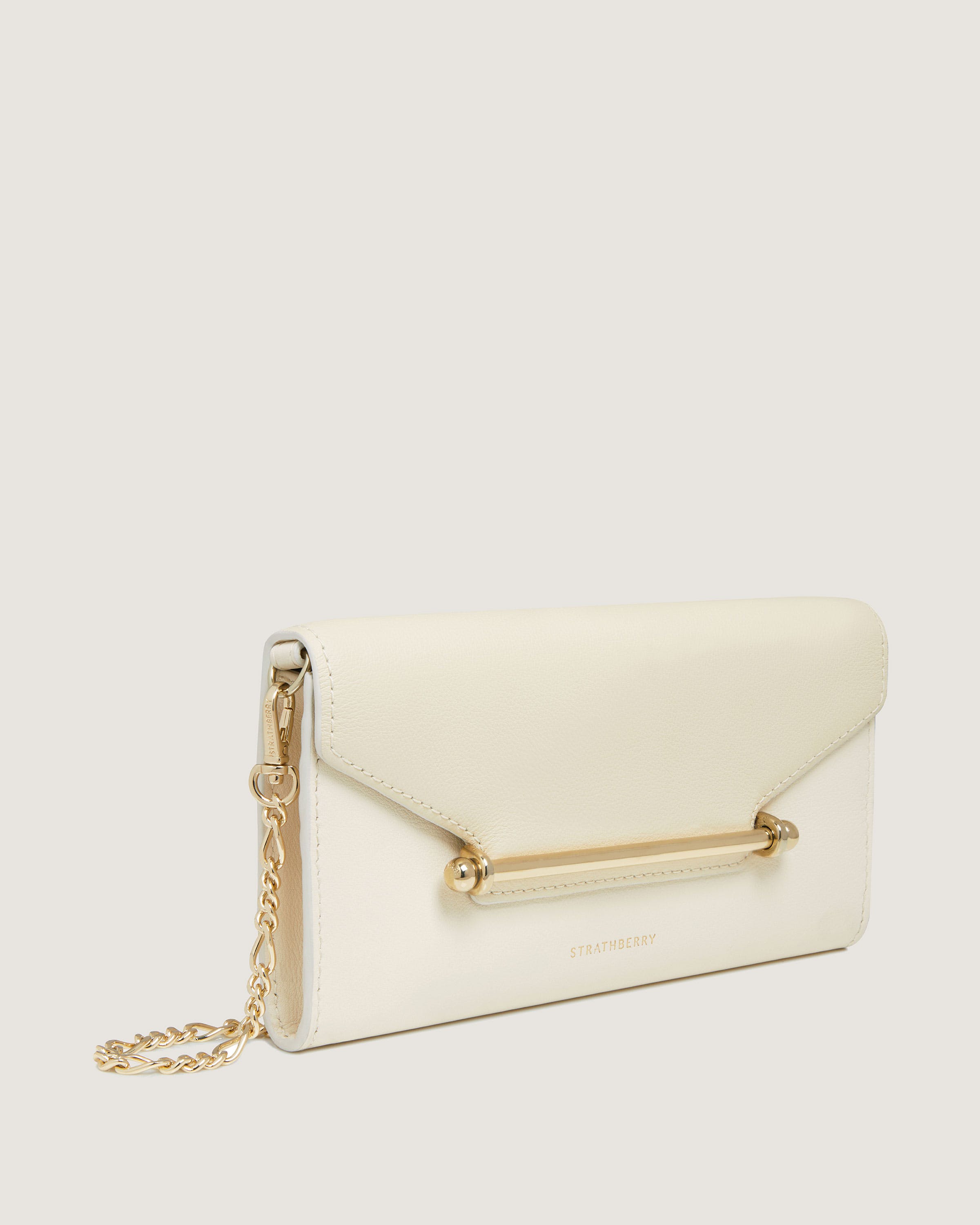 A white purse with a gold chain hanging from it