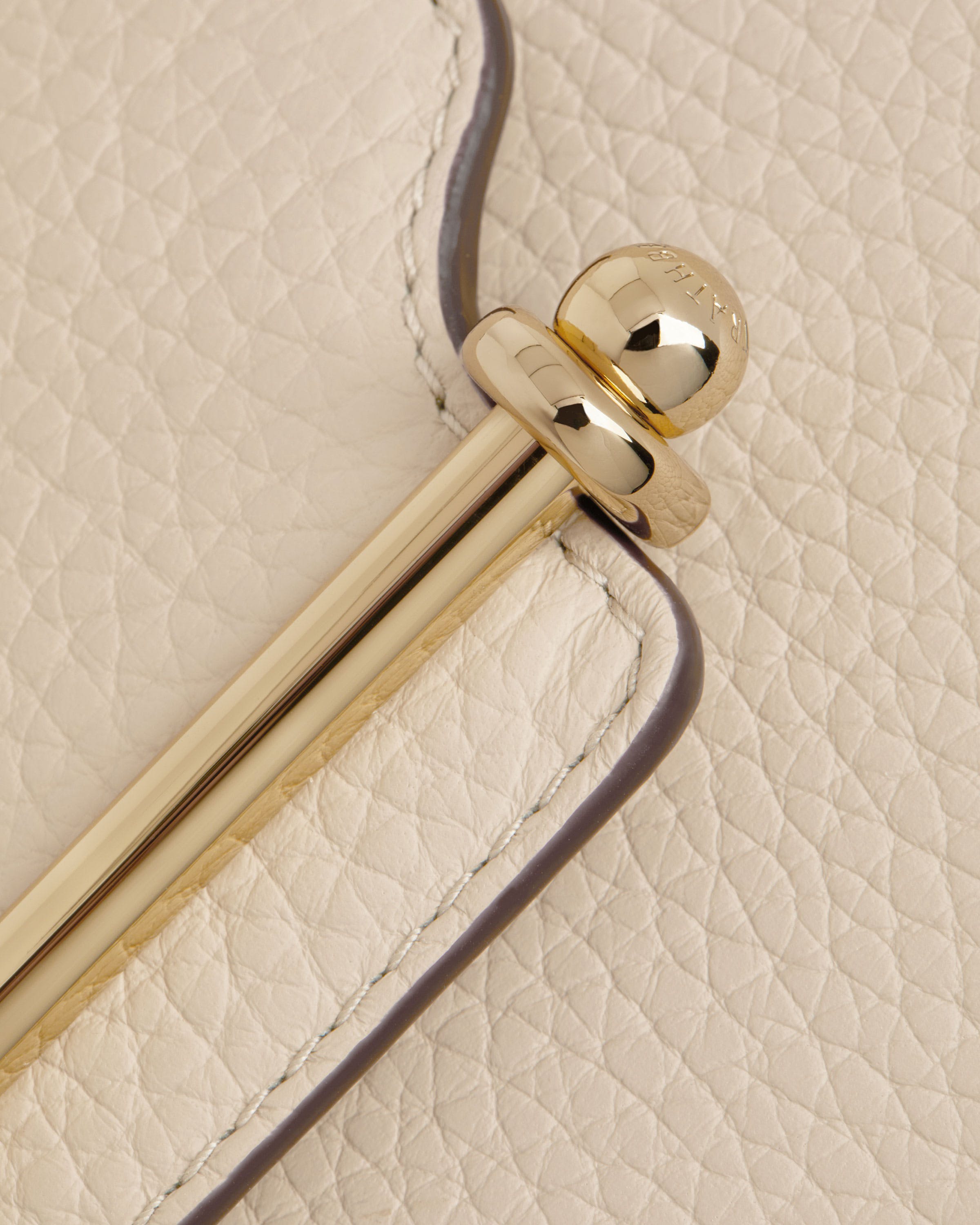 A close up of a white purse with a metal handle