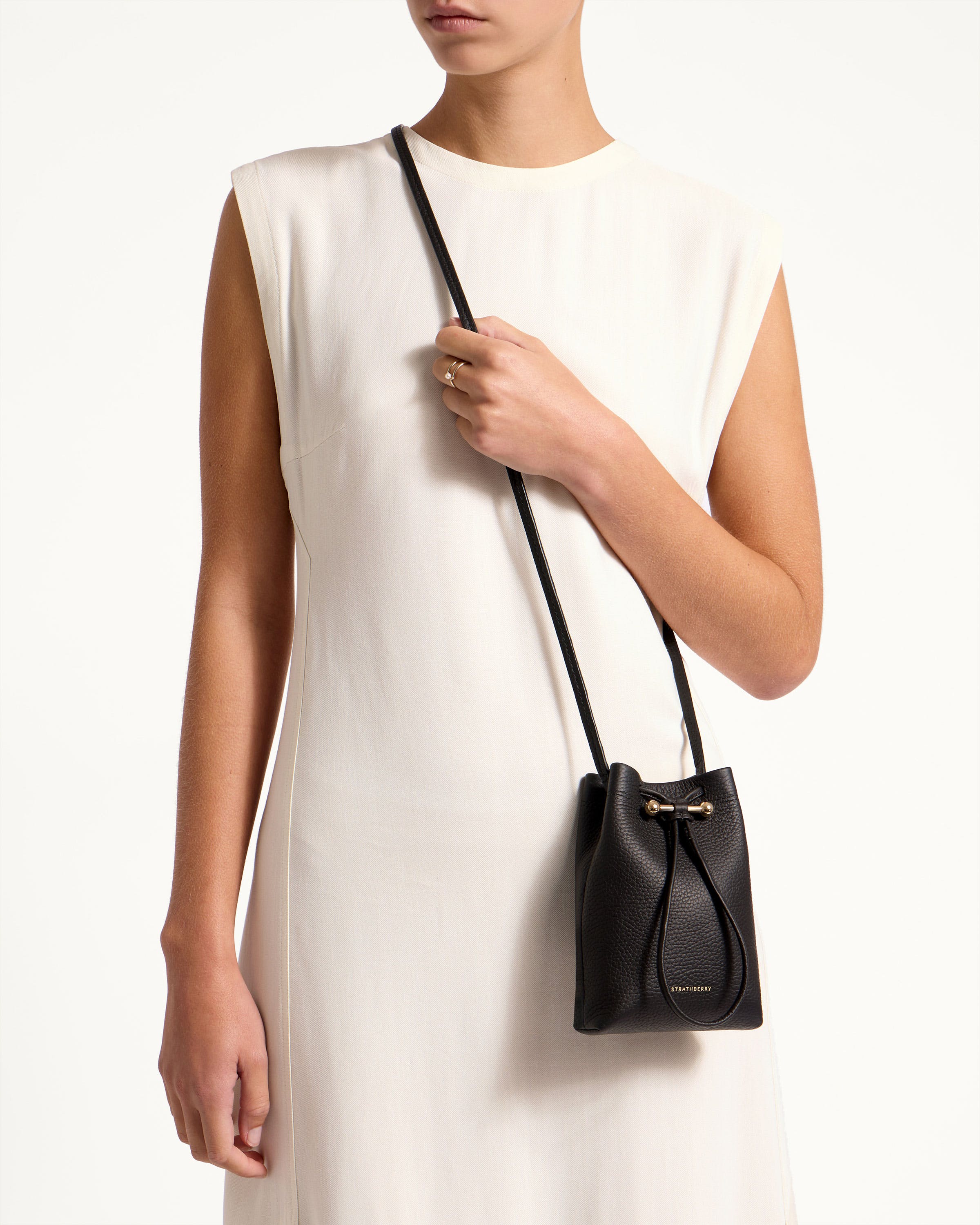 A woman in a white dress holding a black purse