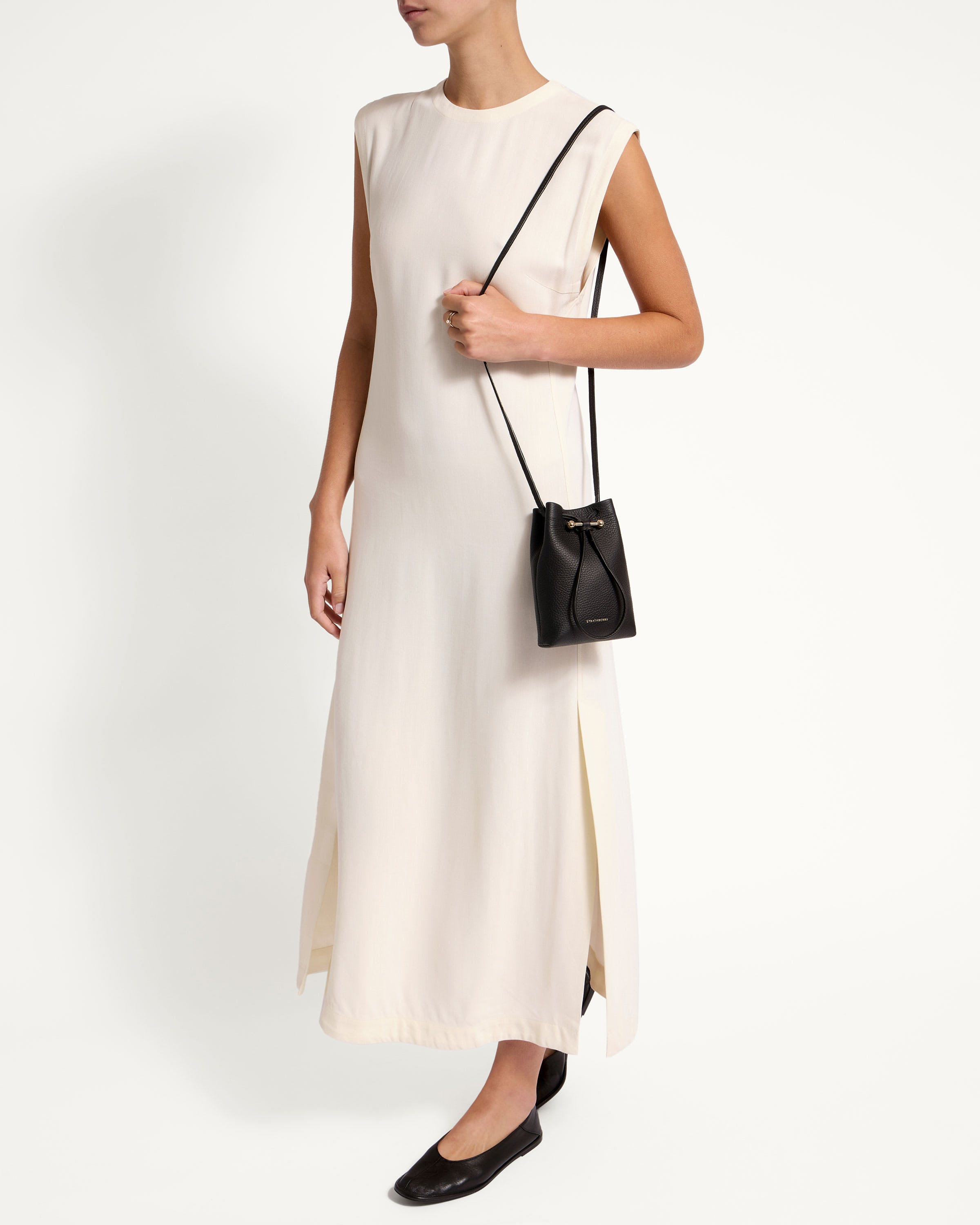 A woman in a white dress holding a black purse