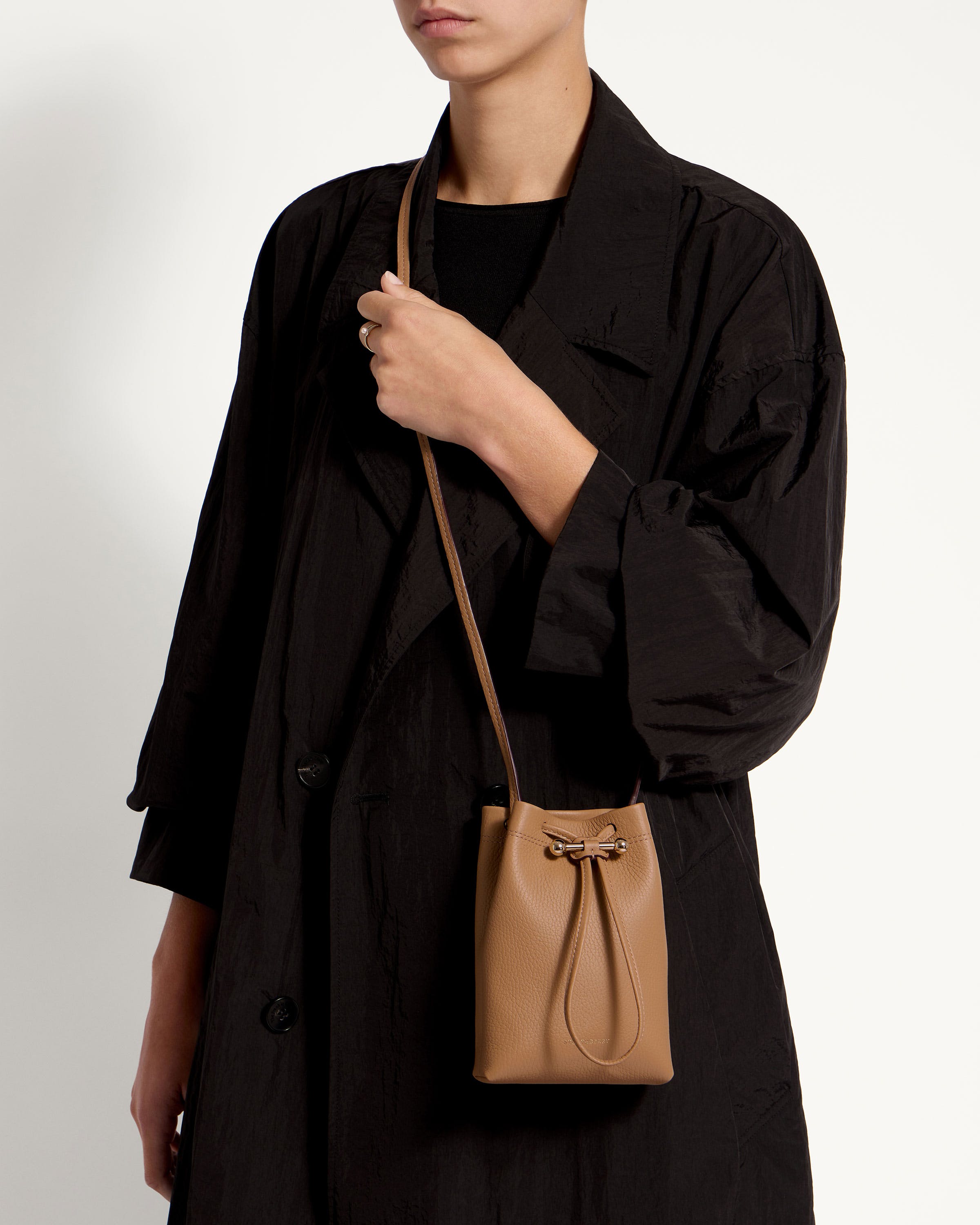 A woman is holding a brown handbag