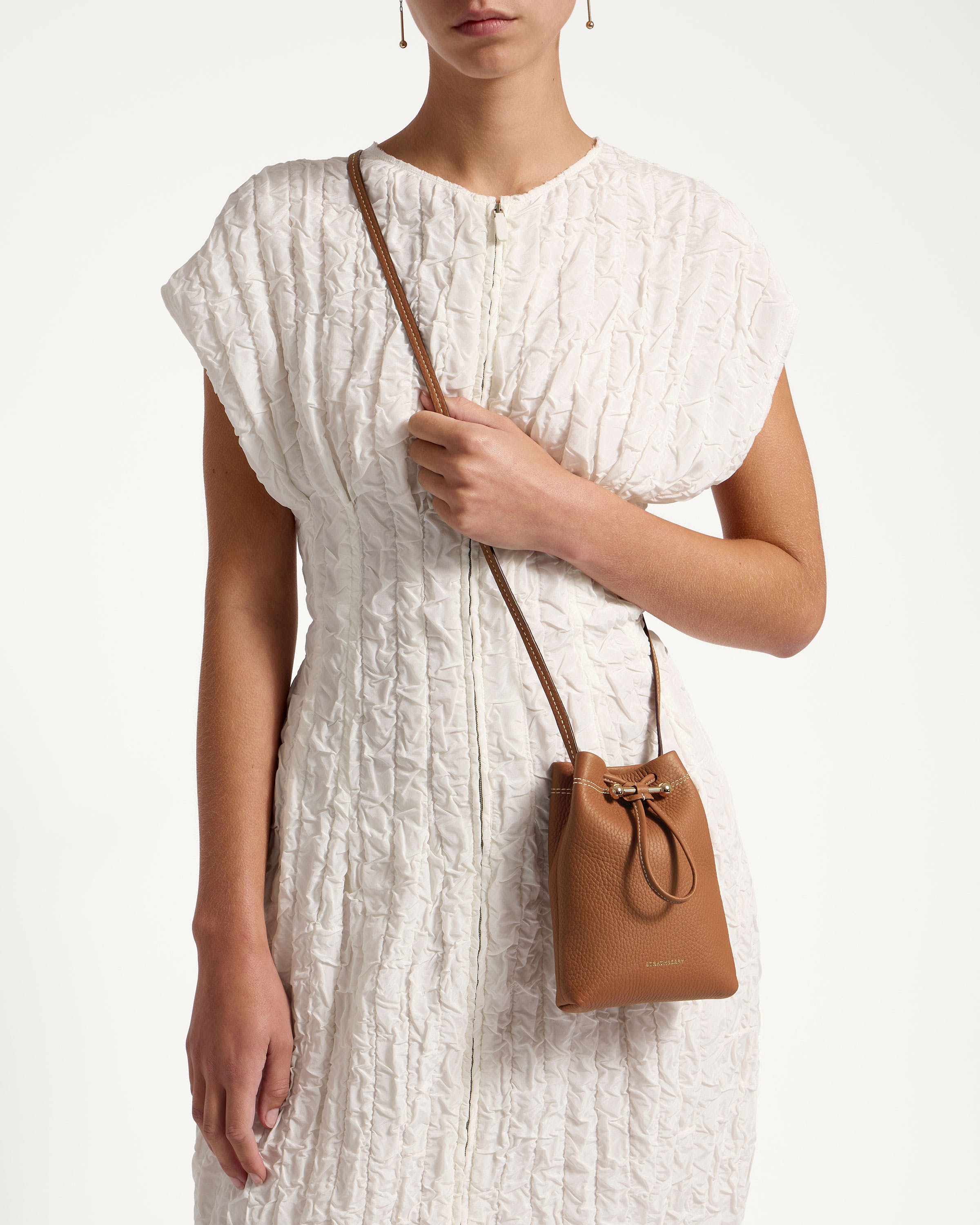 A woman in a white dress holding a brown purse