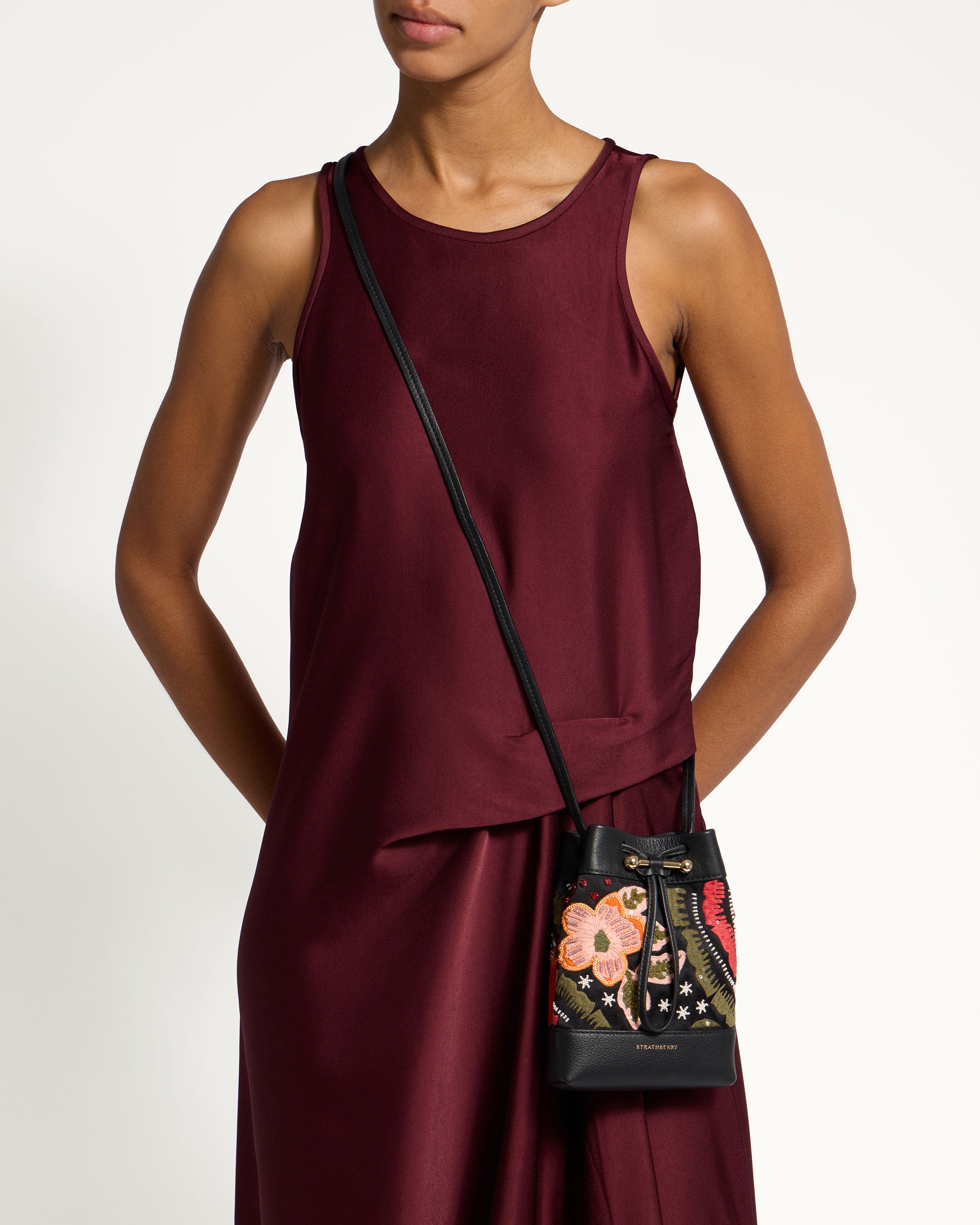 A woman in a maroon dress holding a black purse