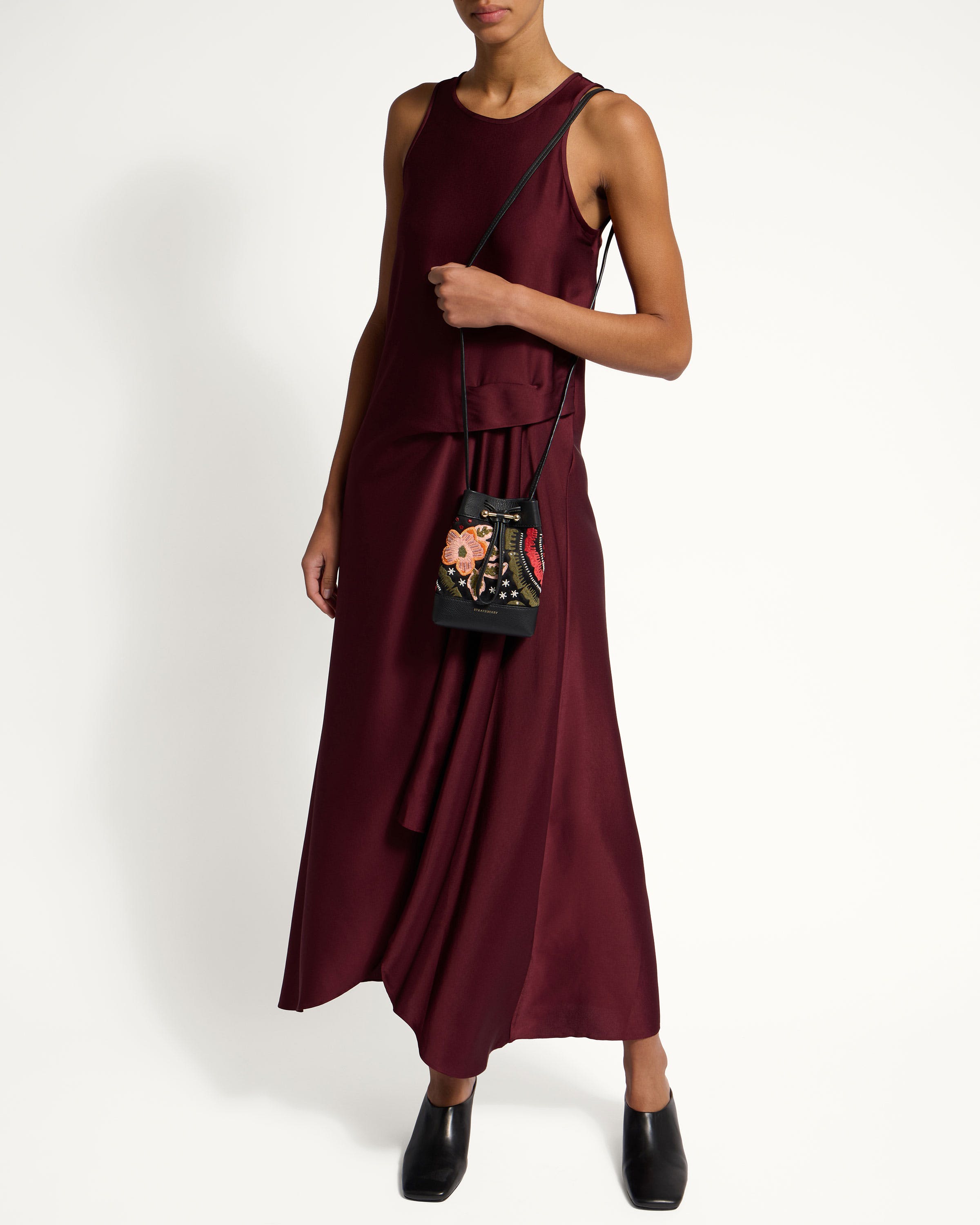 A woman in a maroon dress holding a handbag