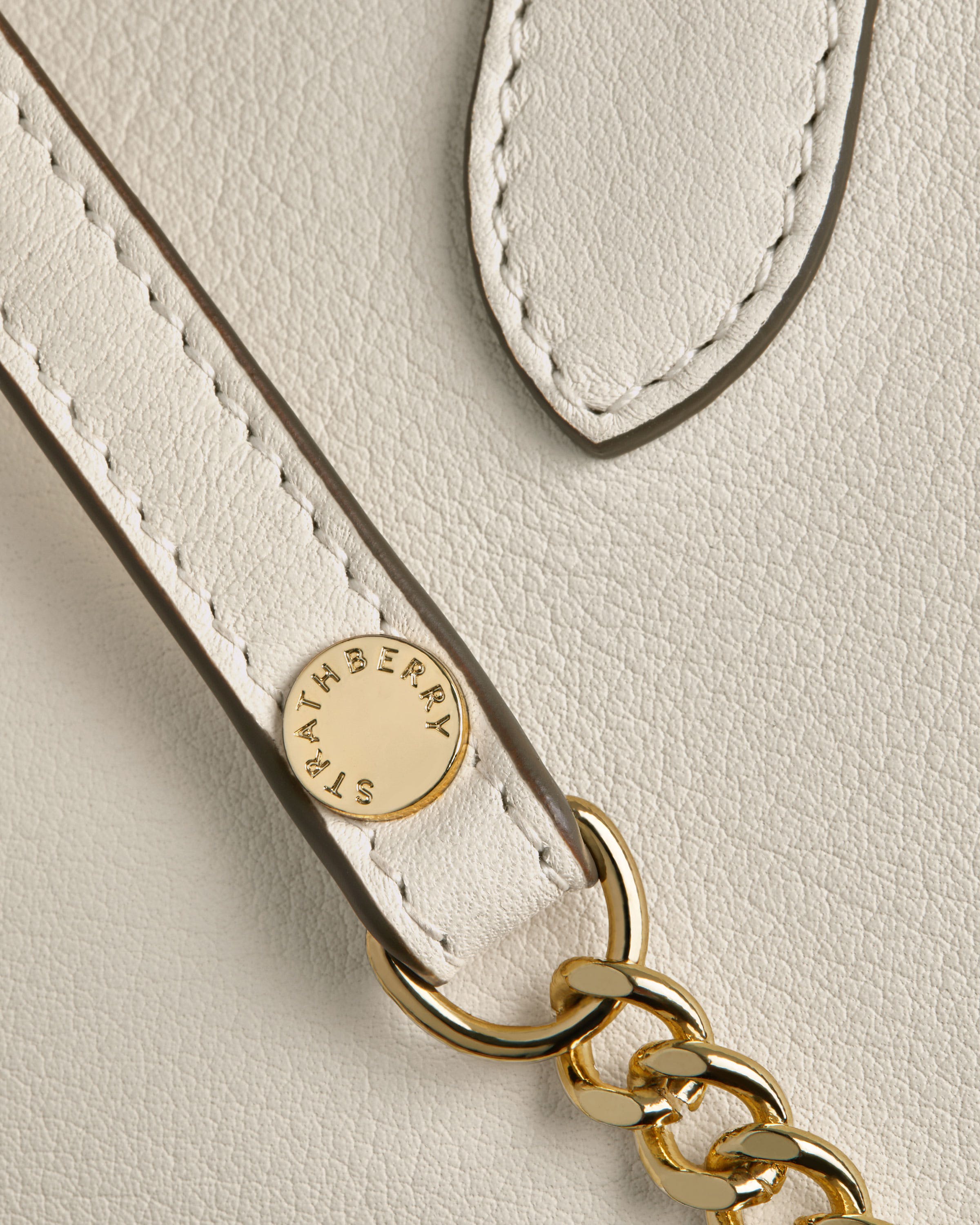 A close up of a white purse with a gold chain