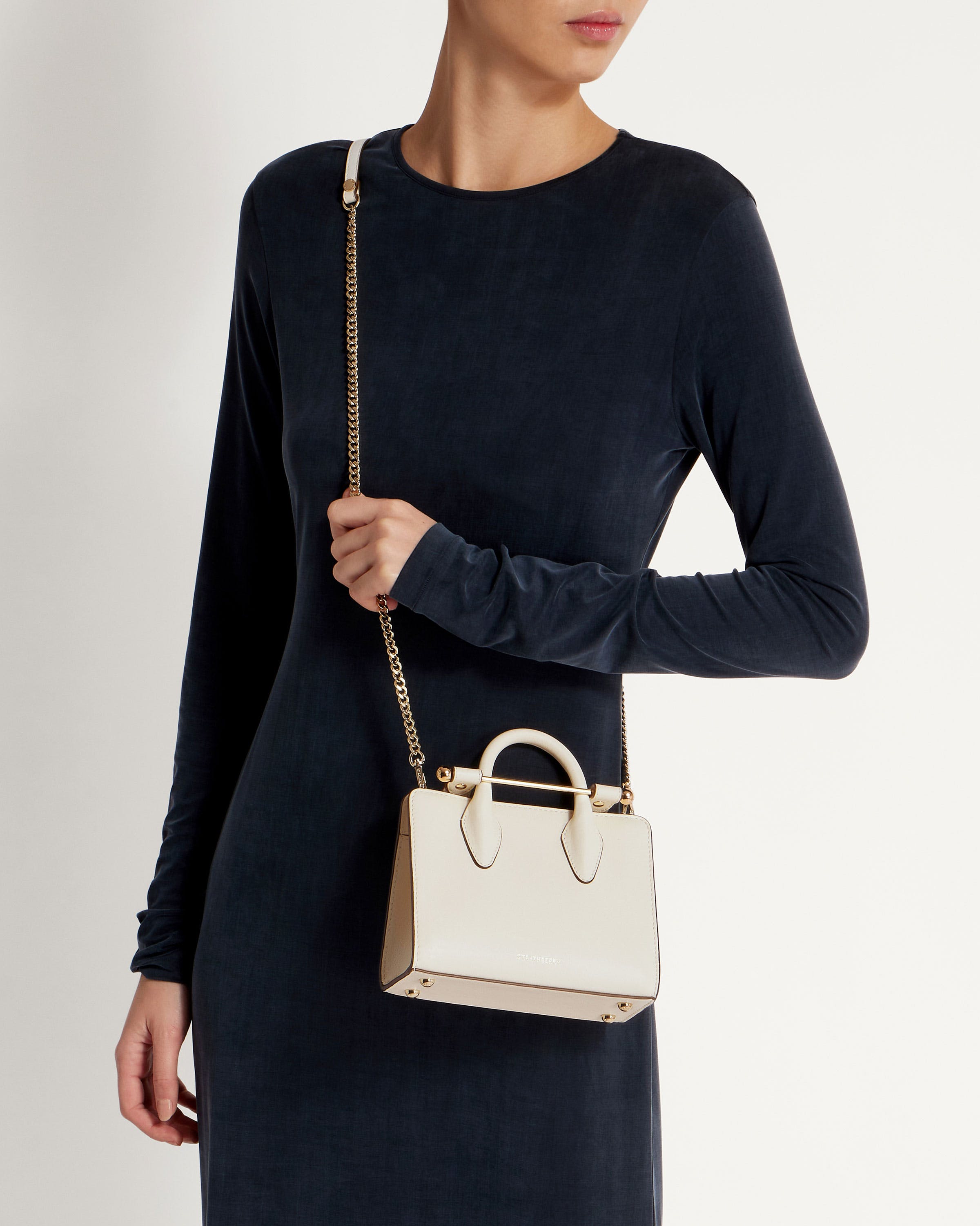 A woman in a black dress holding a white purse