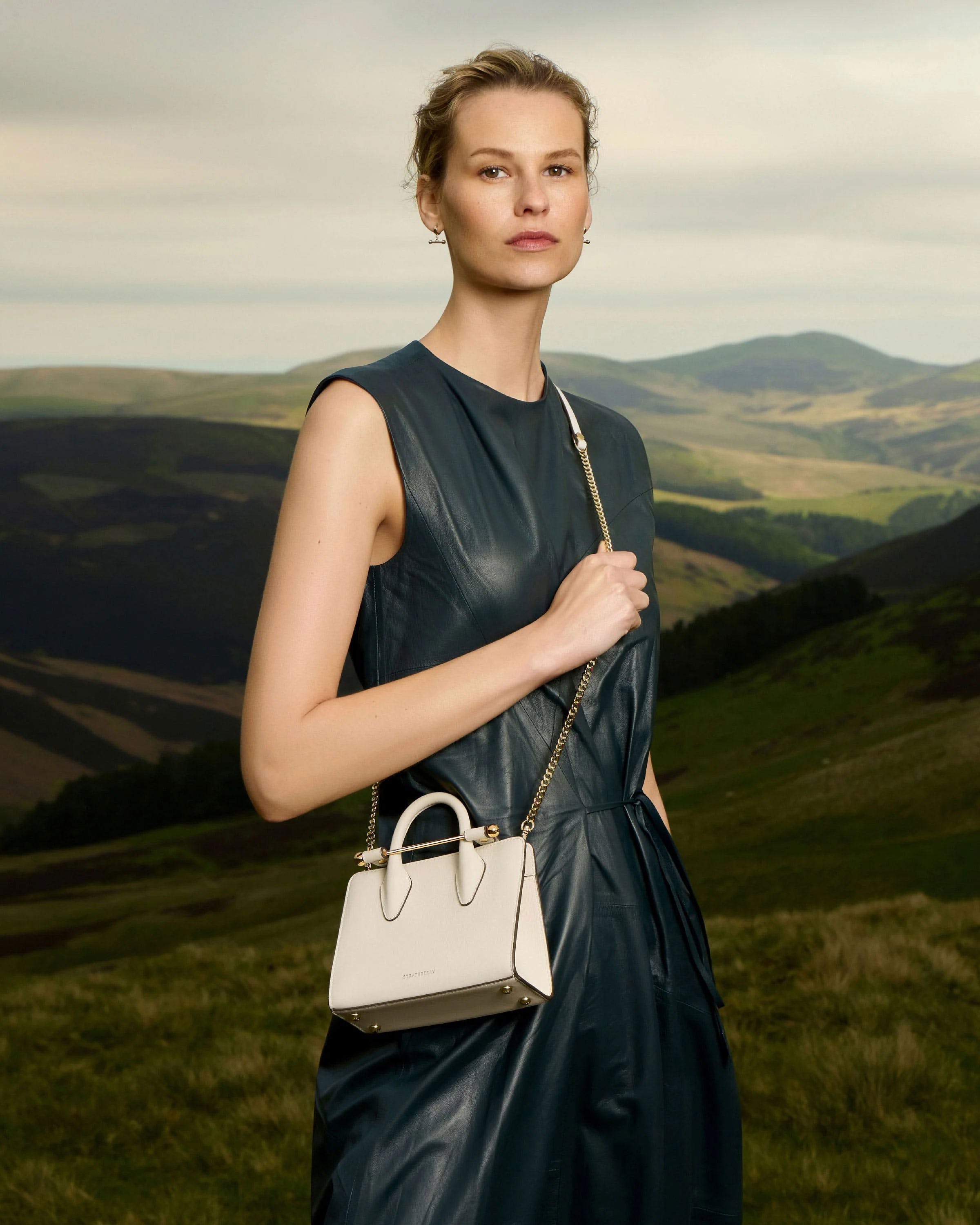 A woman in a black dress holding a white purse