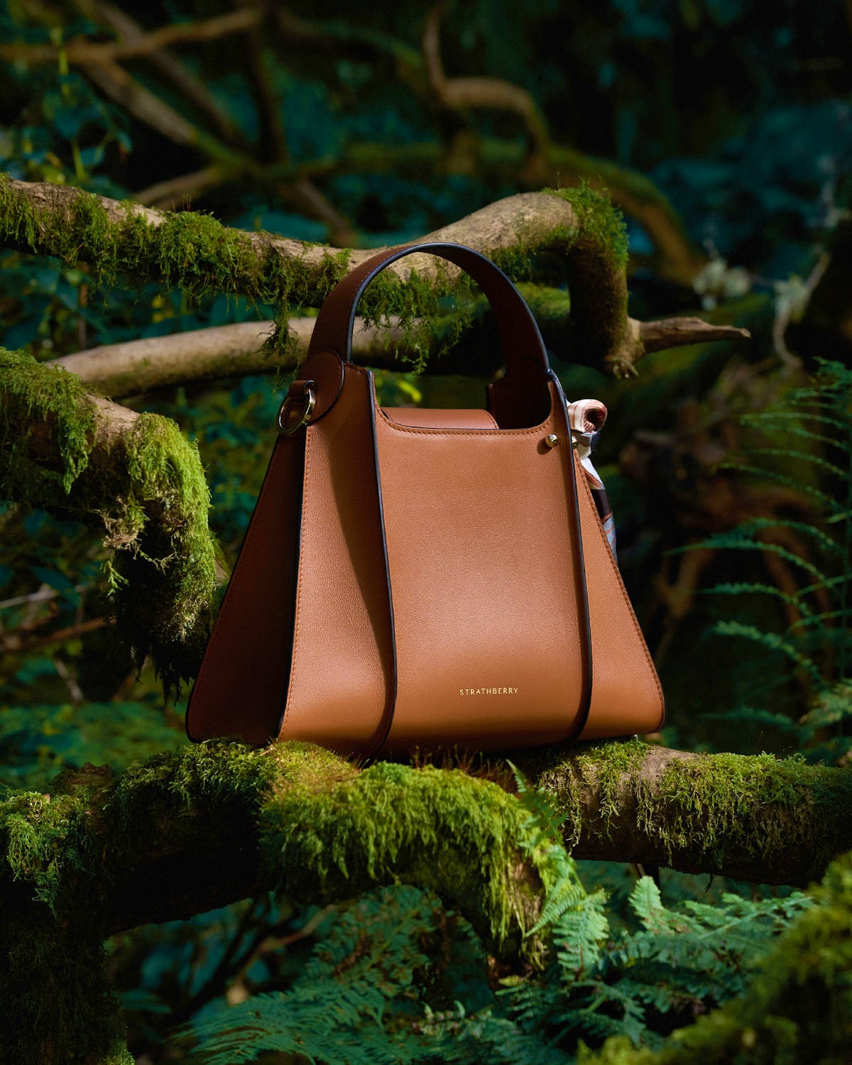 A brown purse sitting on top of a tree branch