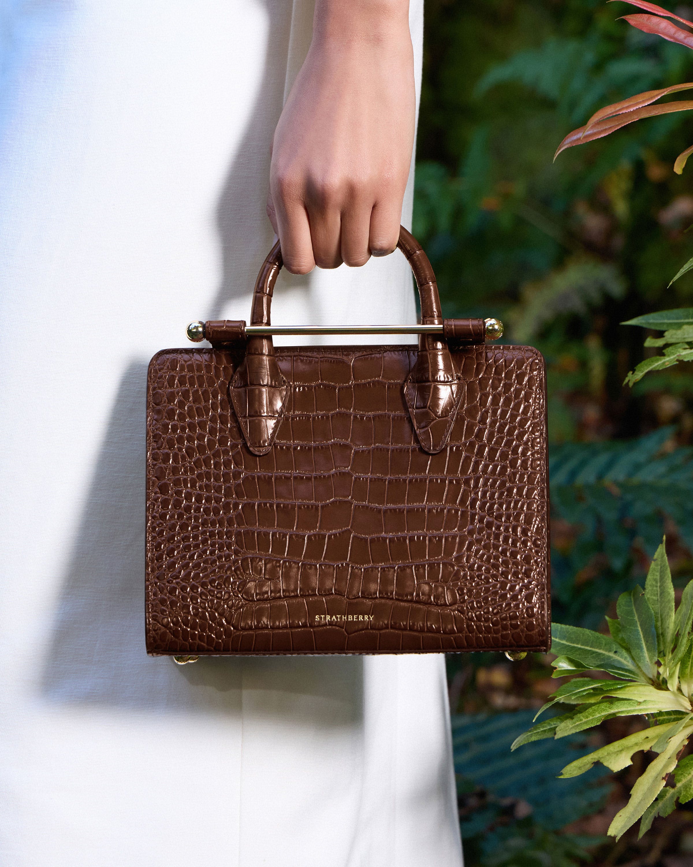 A woman's hand holding a brown purse