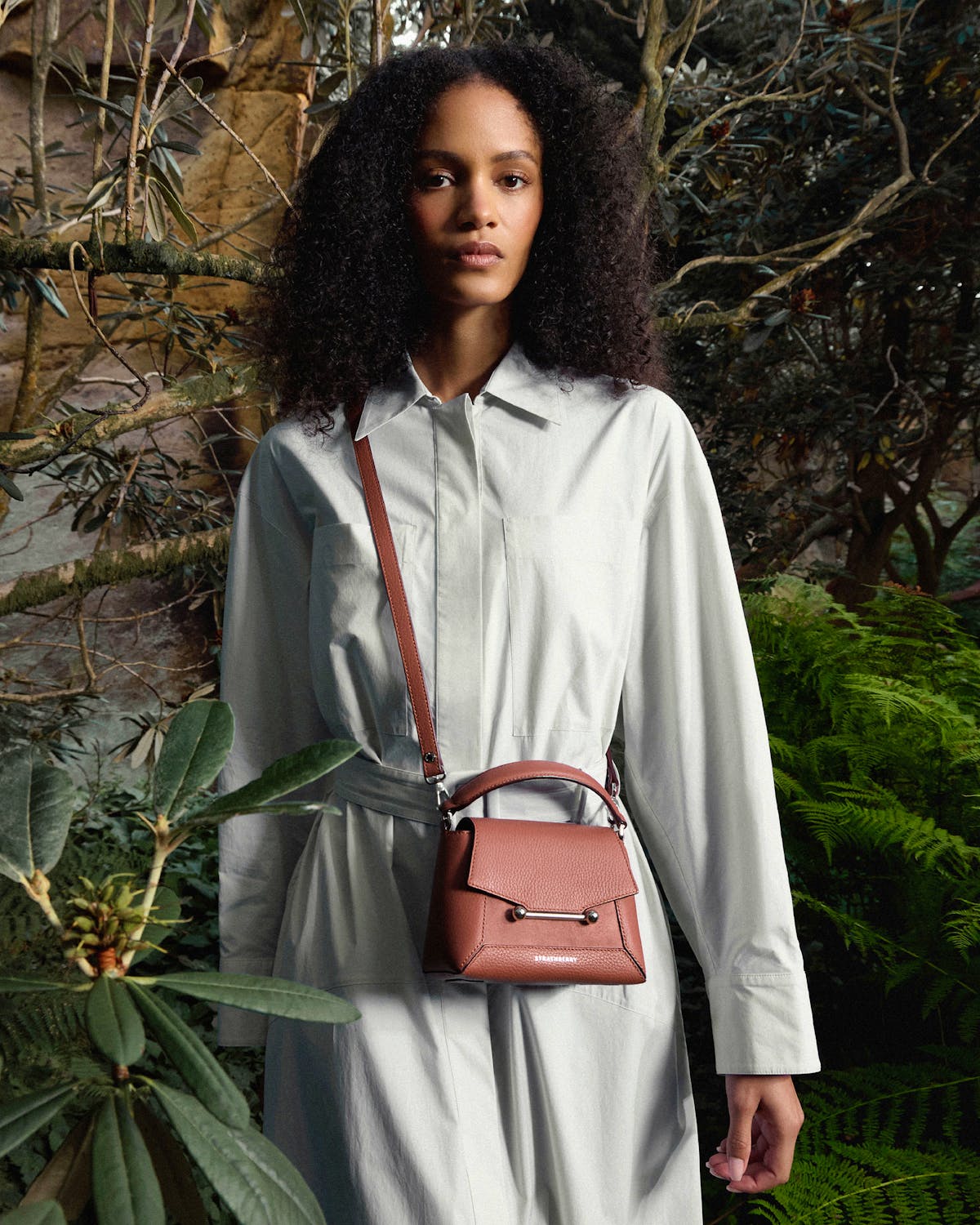 Model wearing belted long-sleeved shirt dress with Strathberry Mosaic Nano sienna dusty pink suede bag.