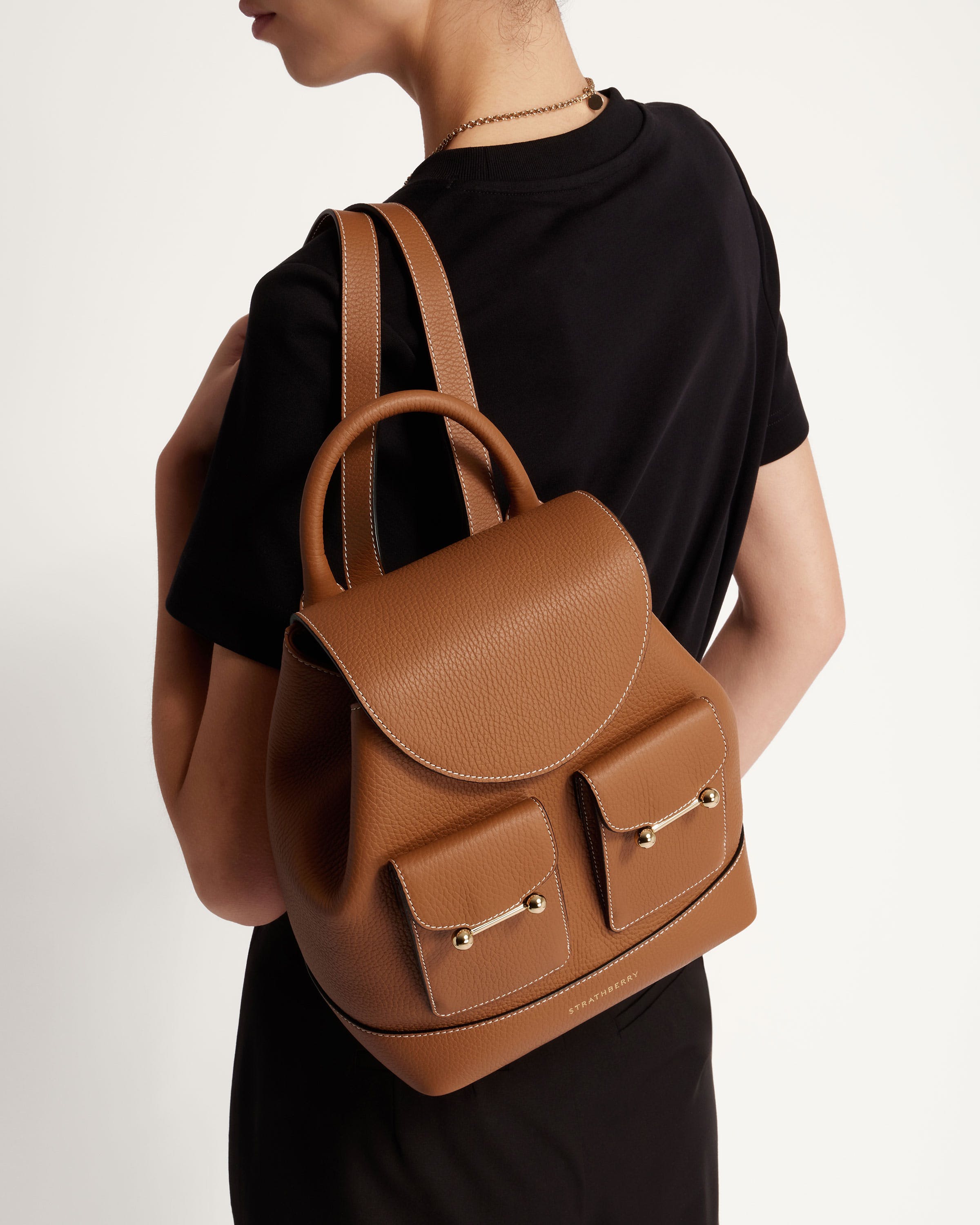 A woman wearing a brown backpack and a black t - shirt