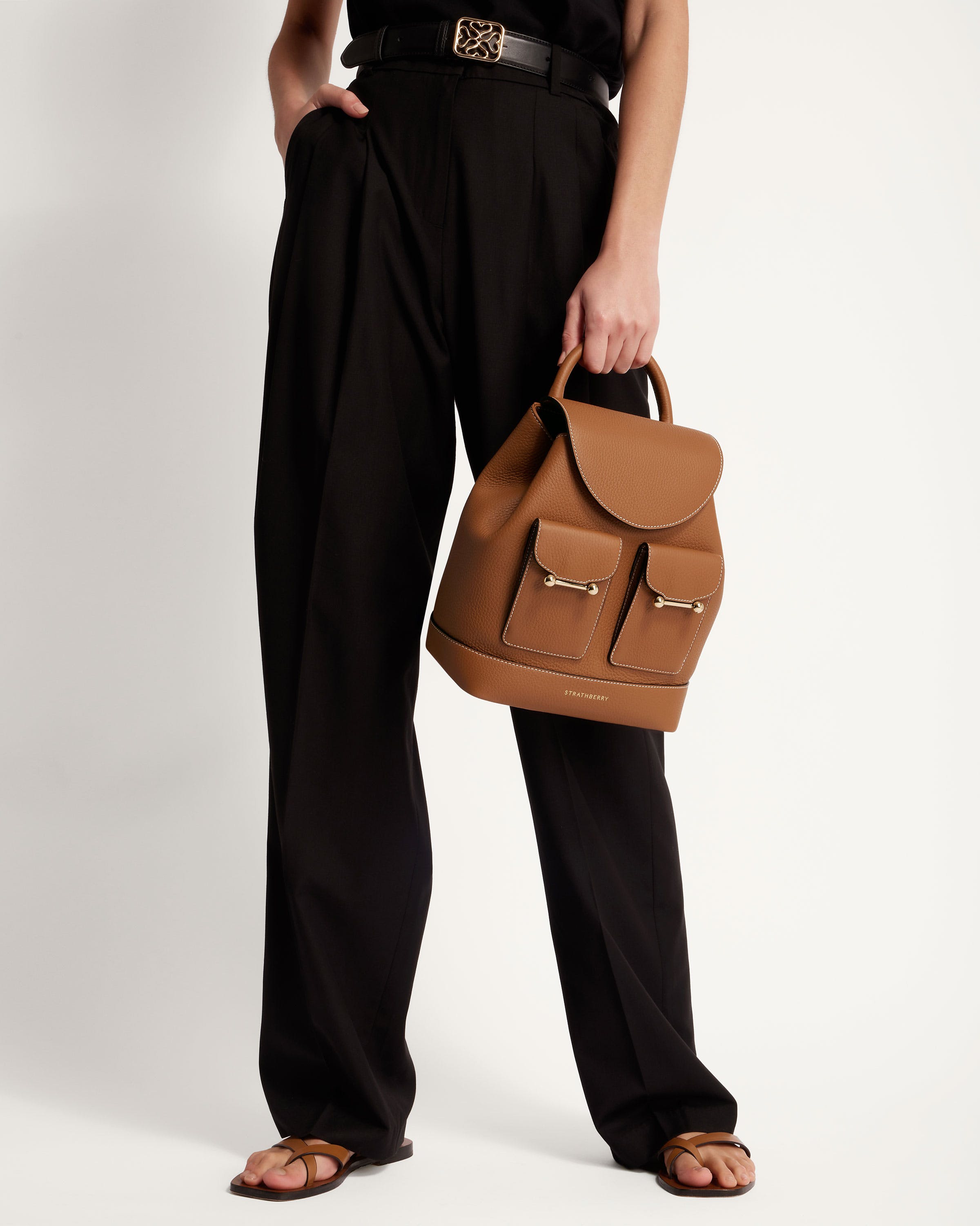 A woman holding a brown handbag in her right hand