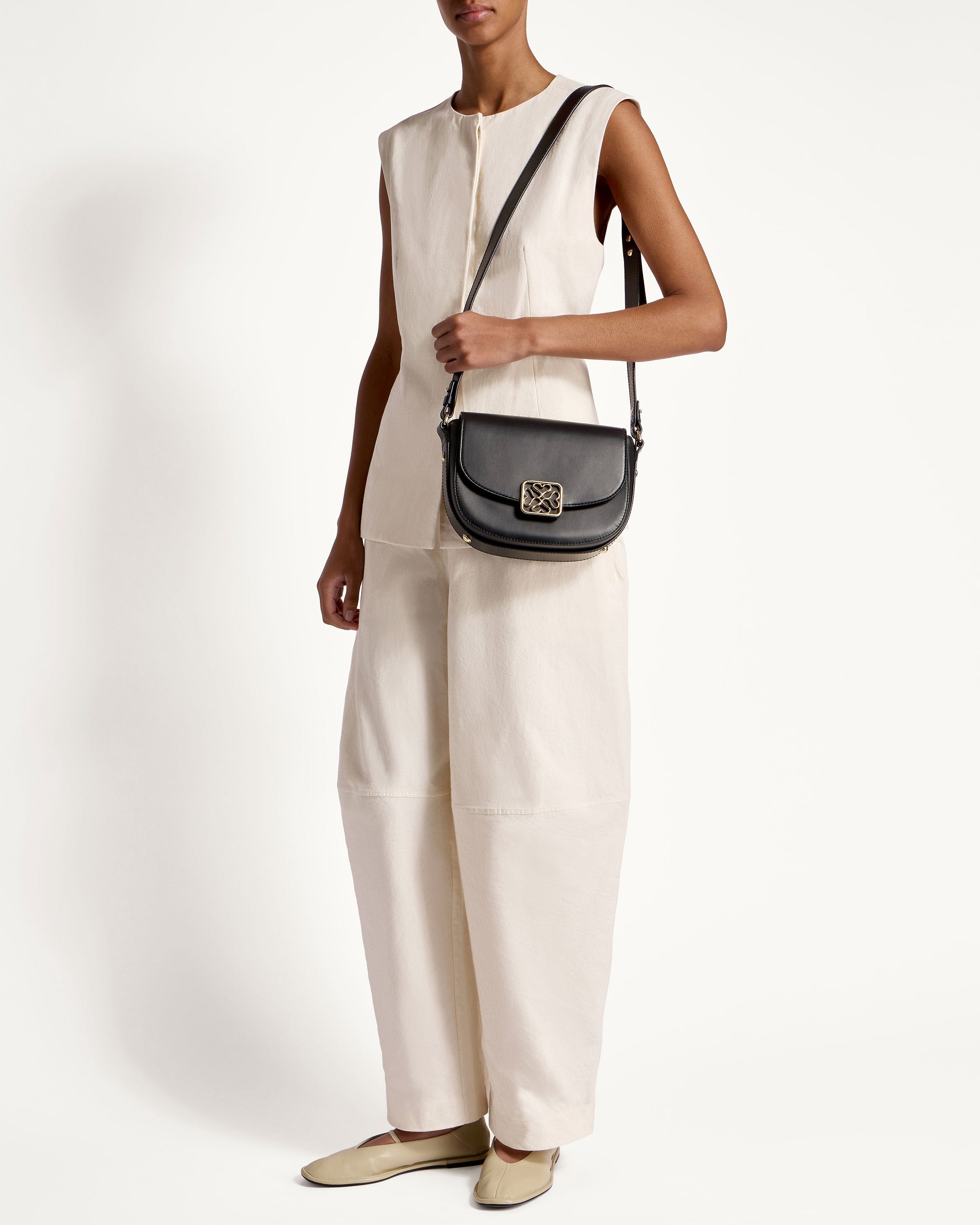 A woman in a white jumpsuit holding a black purse