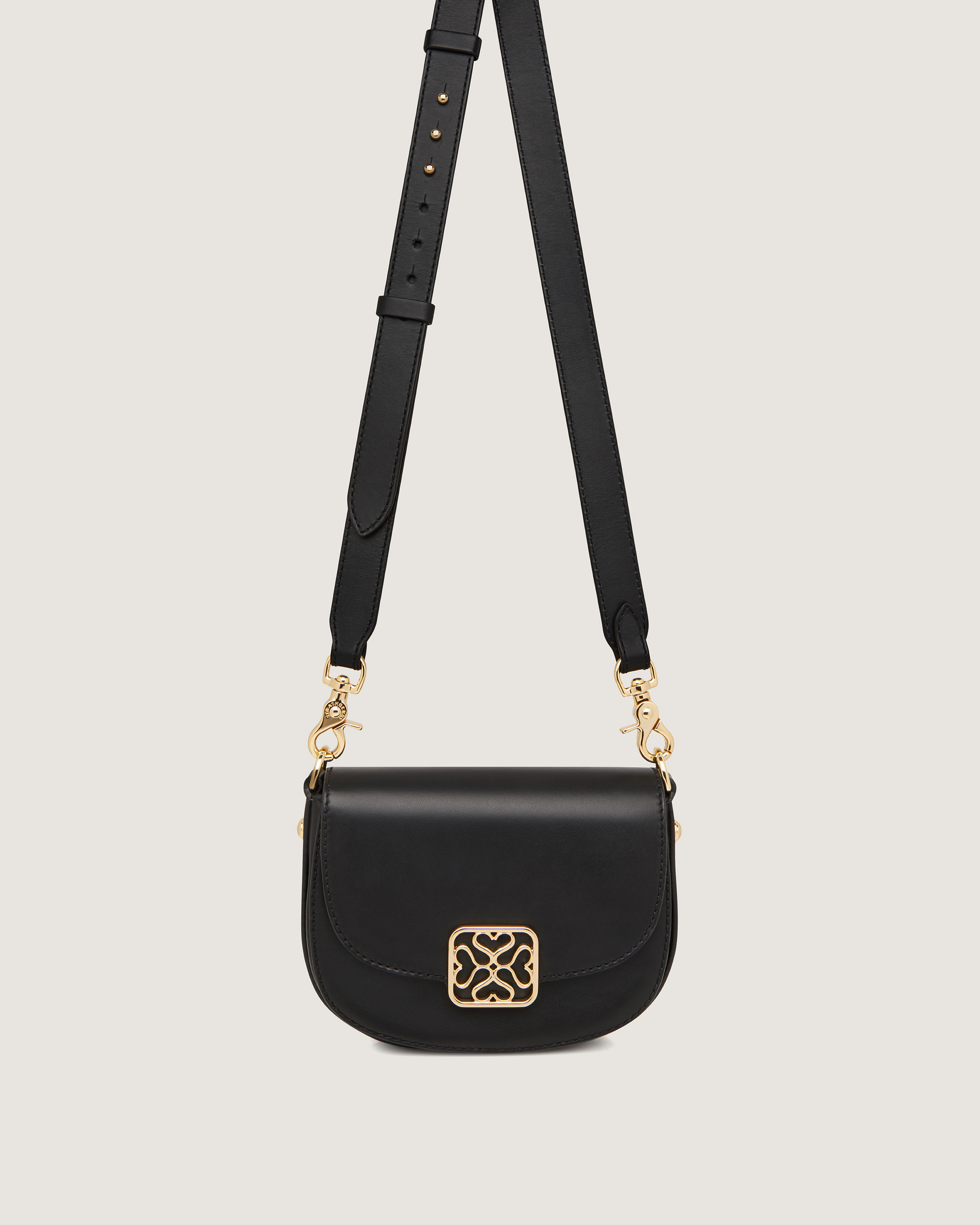 A black cross body bag with a gold buckle