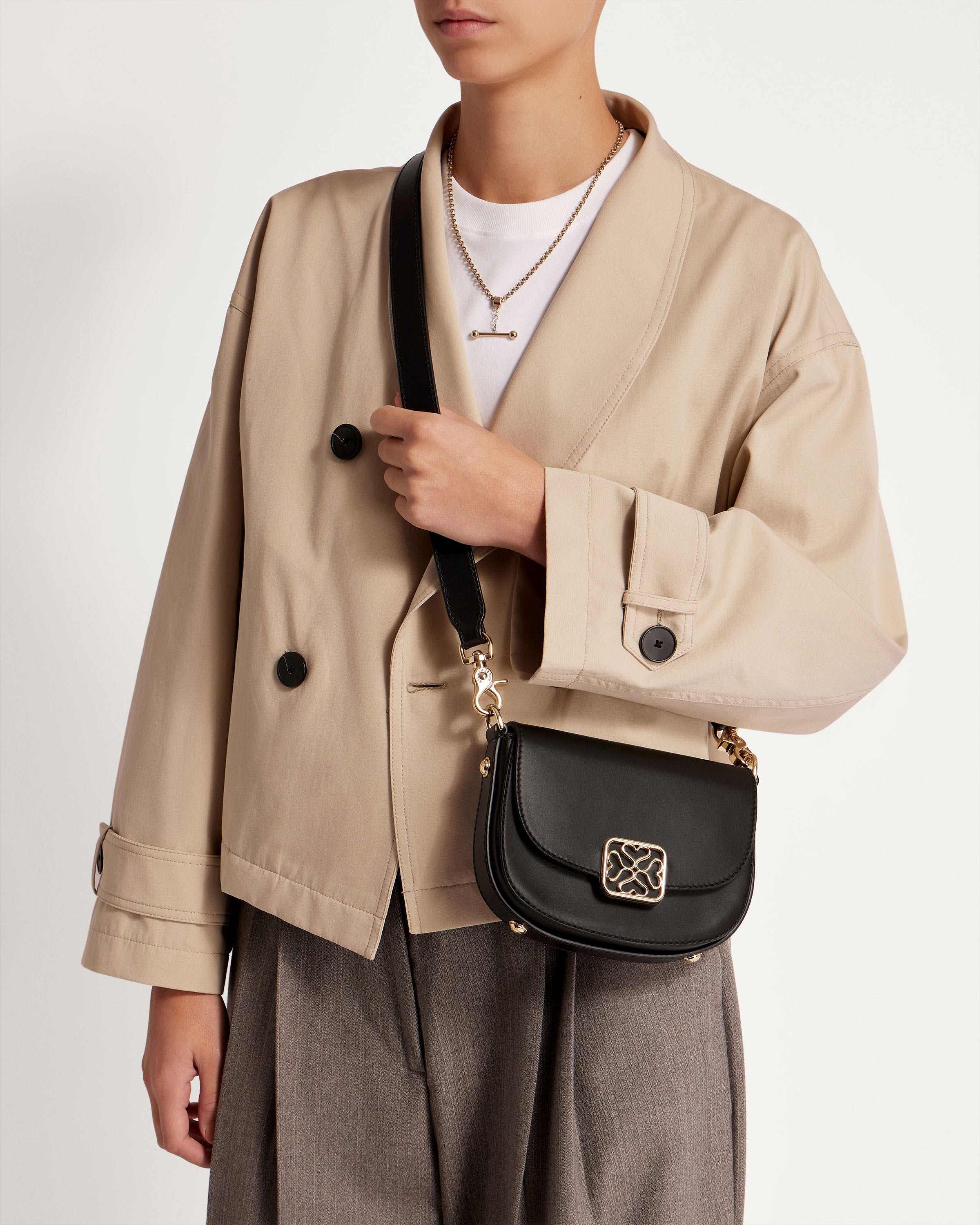 A woman in a beige jacket holding a black purse