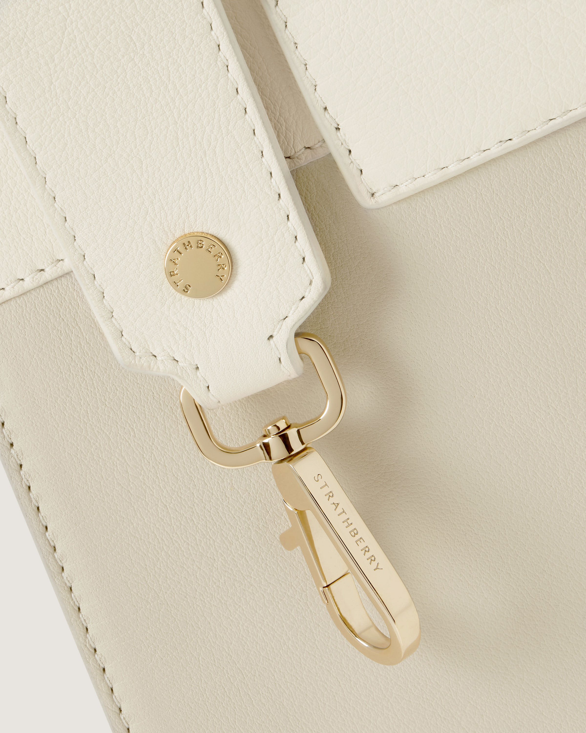 A close up of a white purse with a gold handle