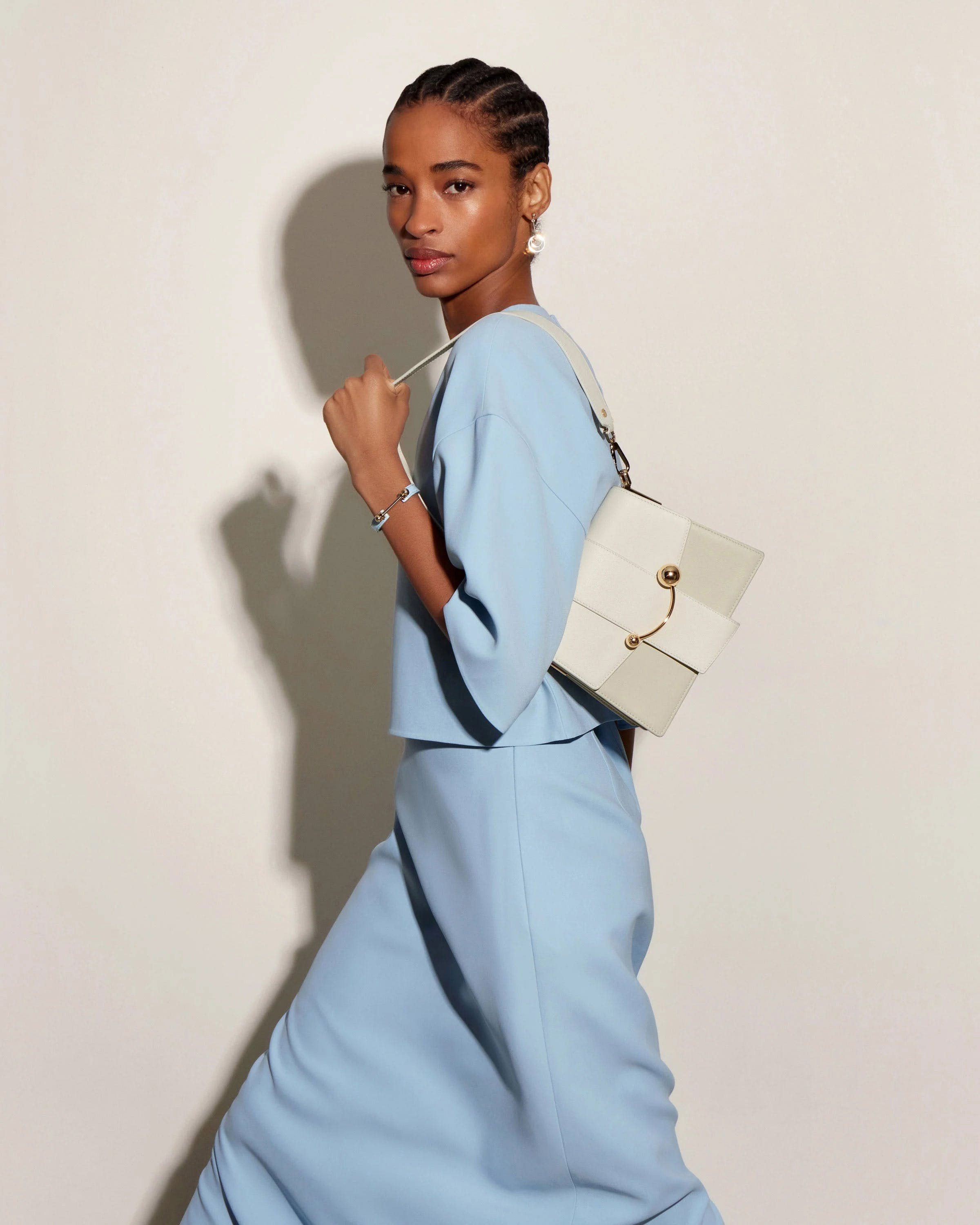 A woman in a blue dress is holding a white purse