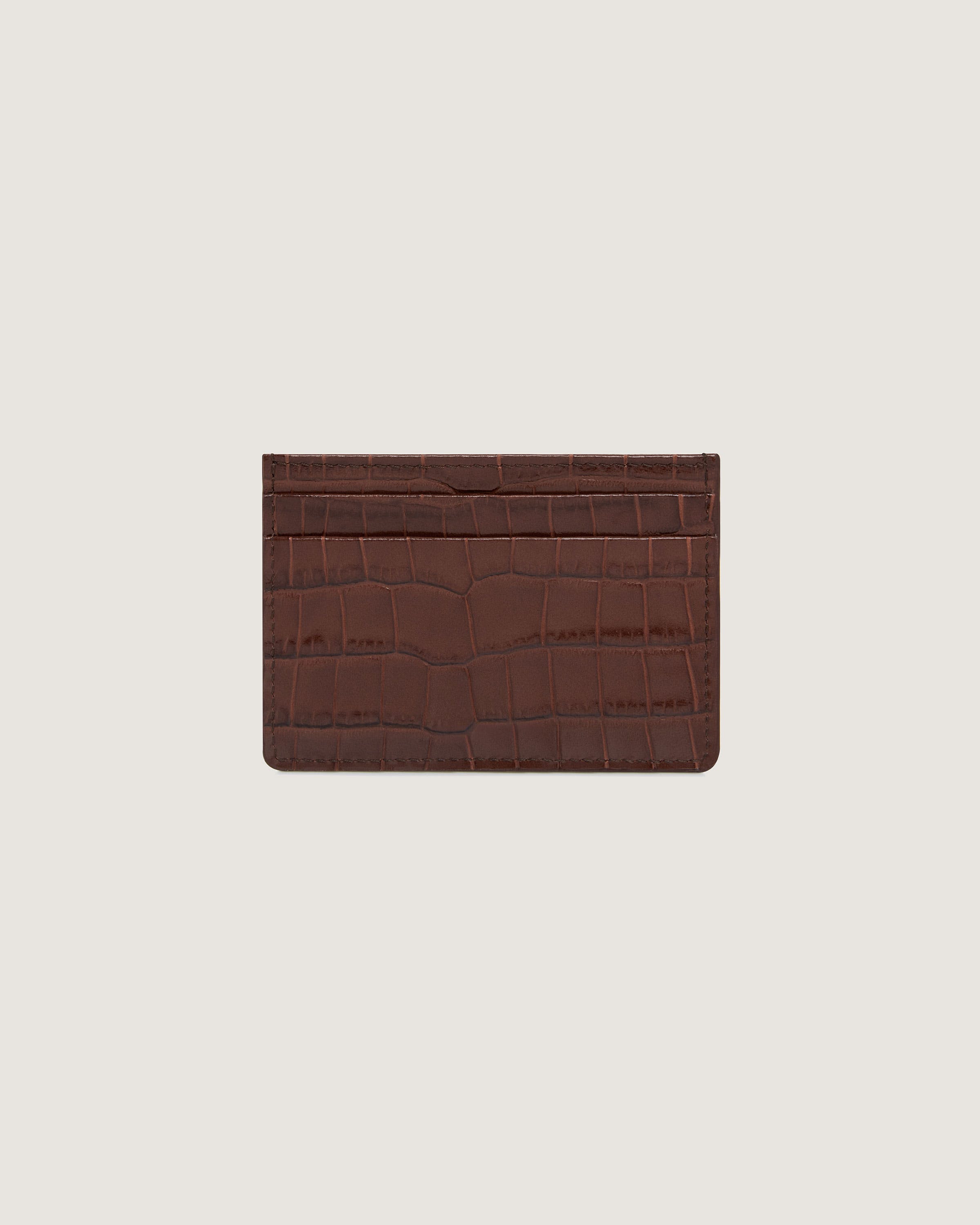 A brown alligator skin card case on a white background