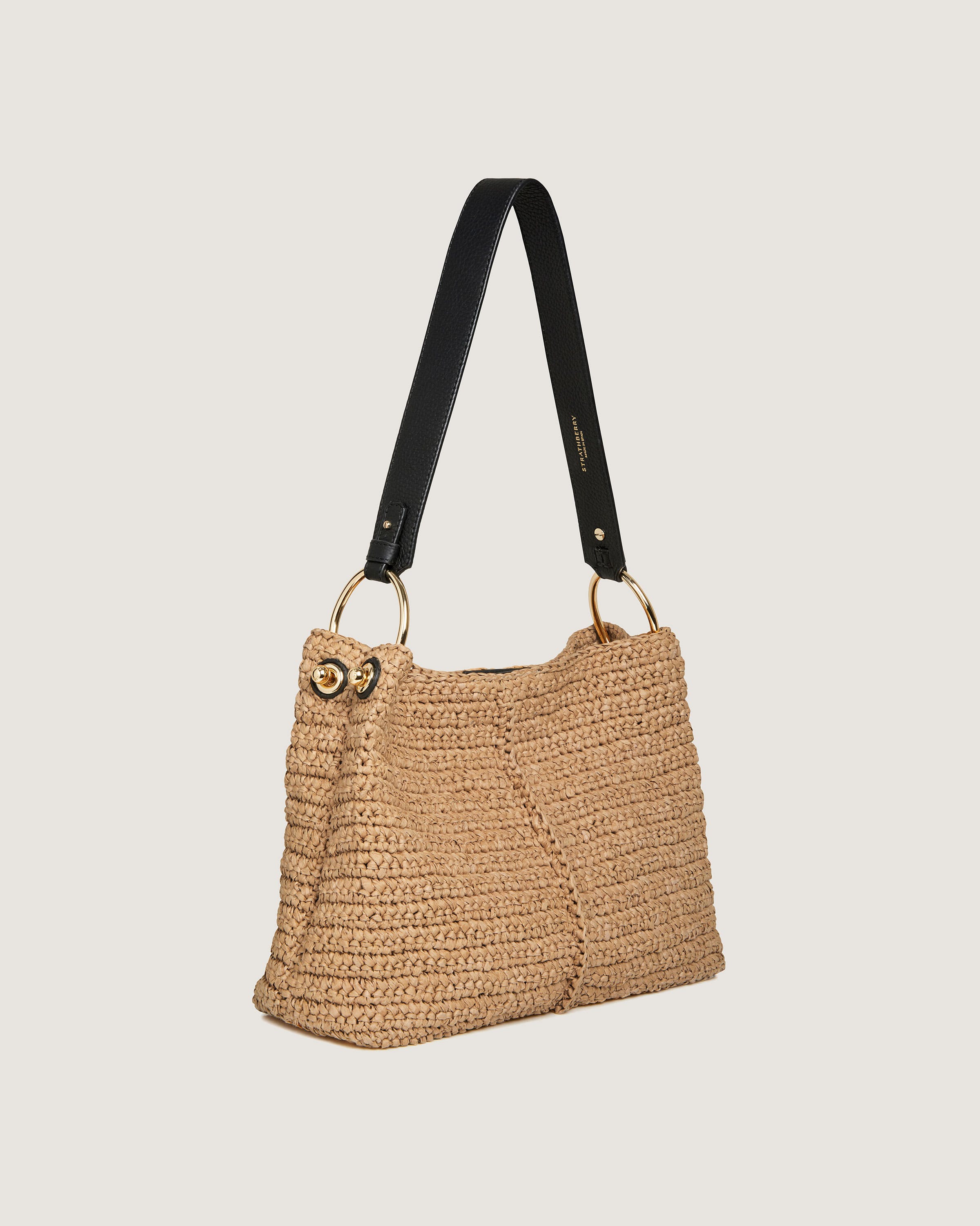 A straw bag with a black strap hanging from it