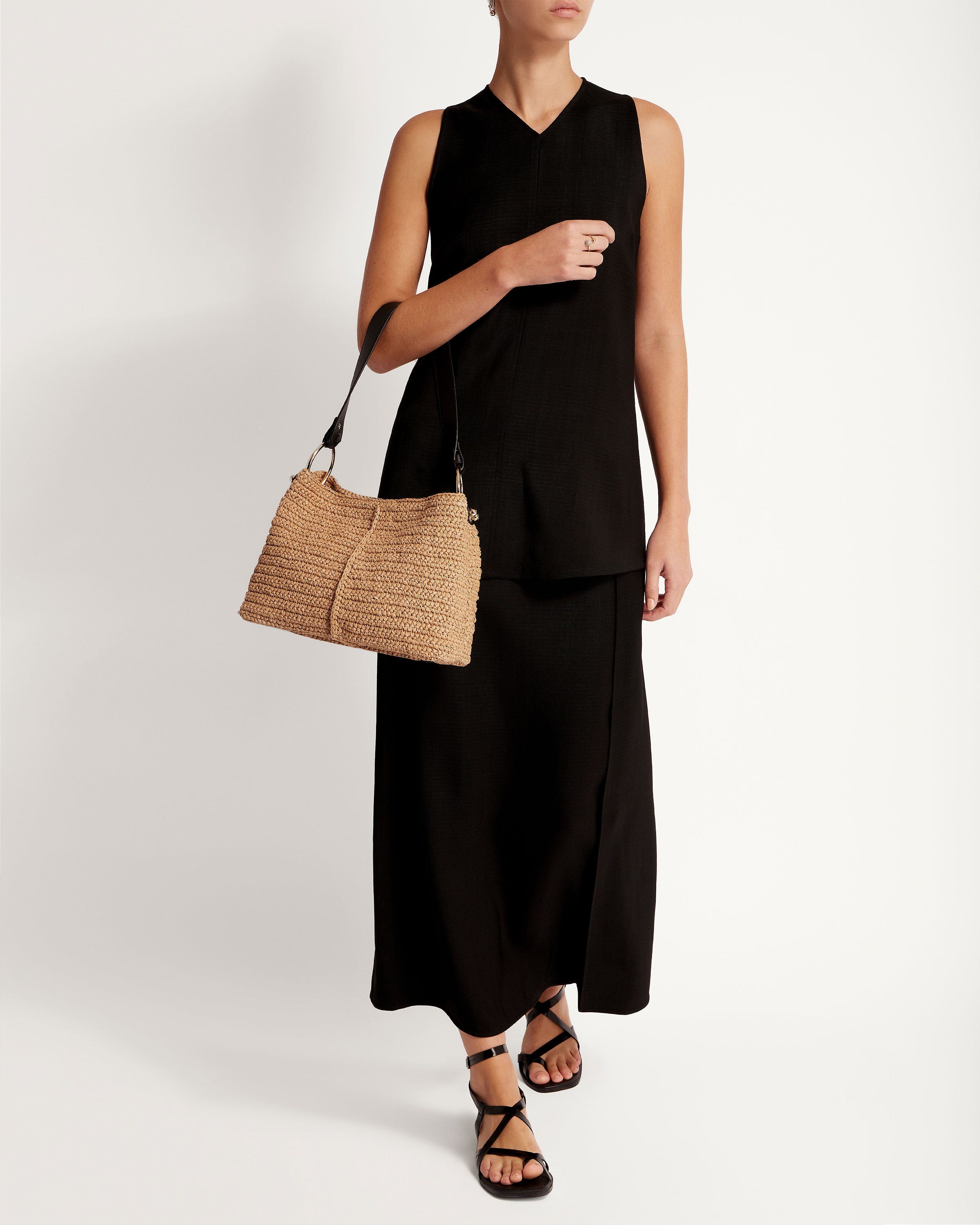 A woman in a black dress holding a straw bag