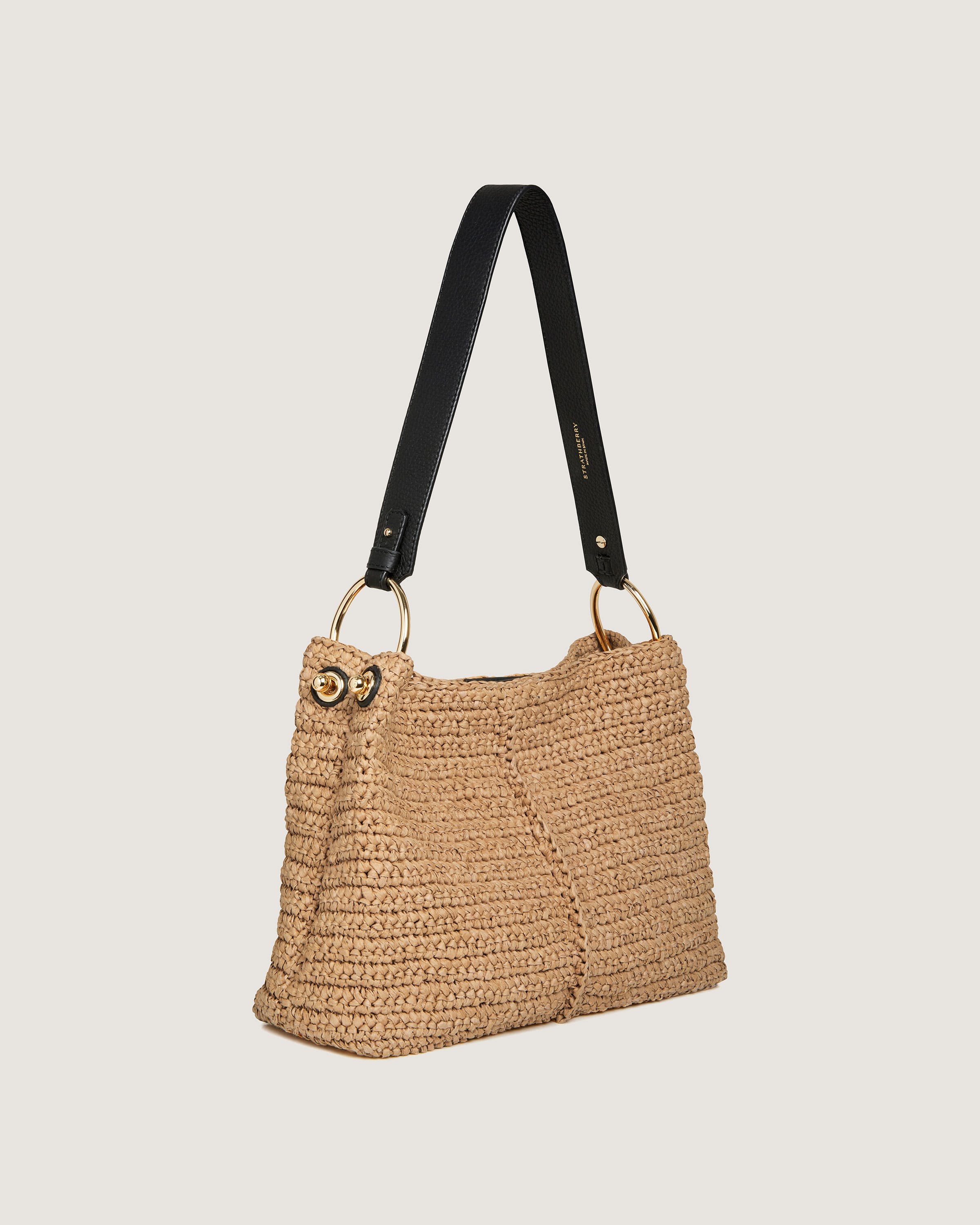 A straw bag with a black strap hanging from it