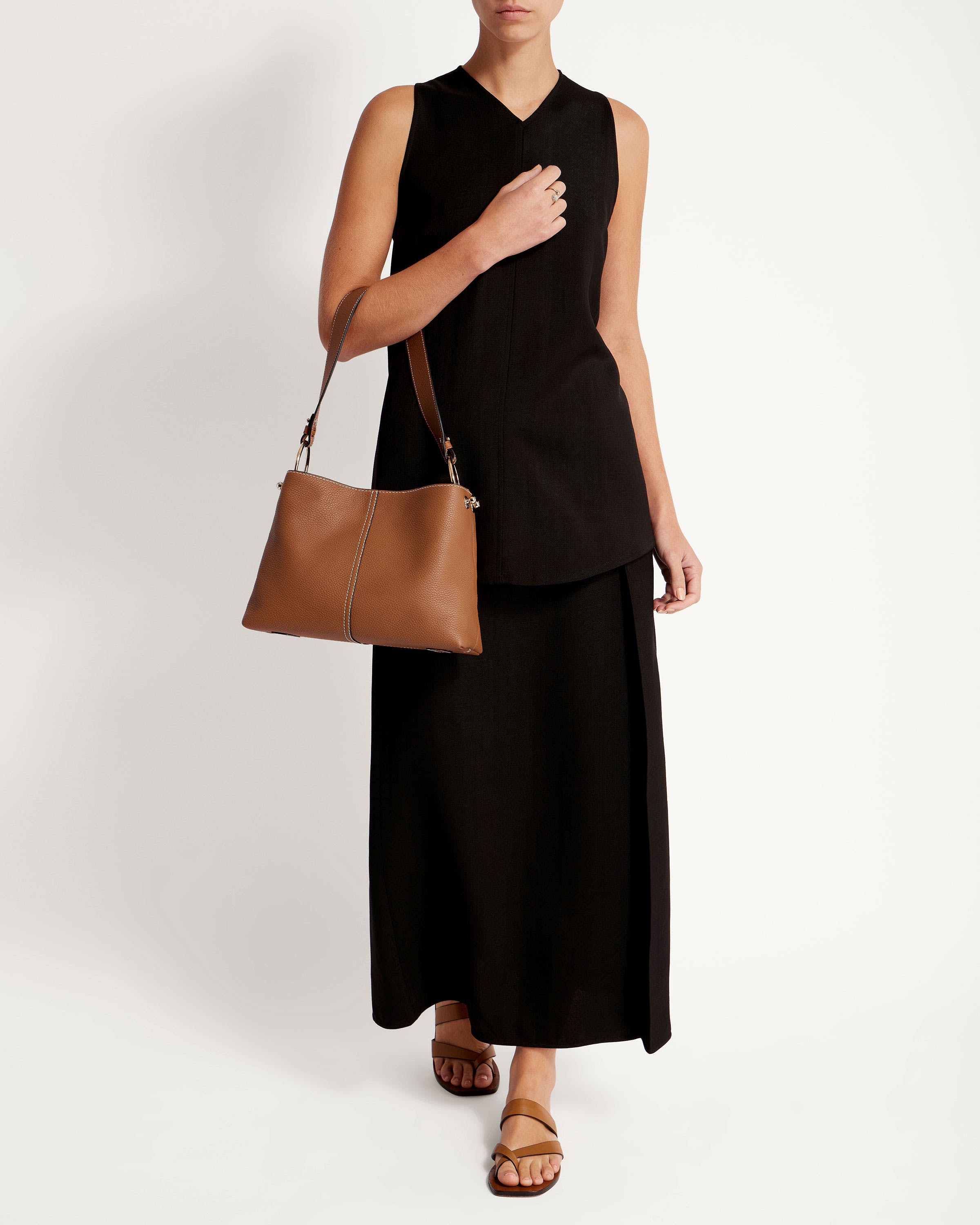 A woman in a black dress holding a brown bag