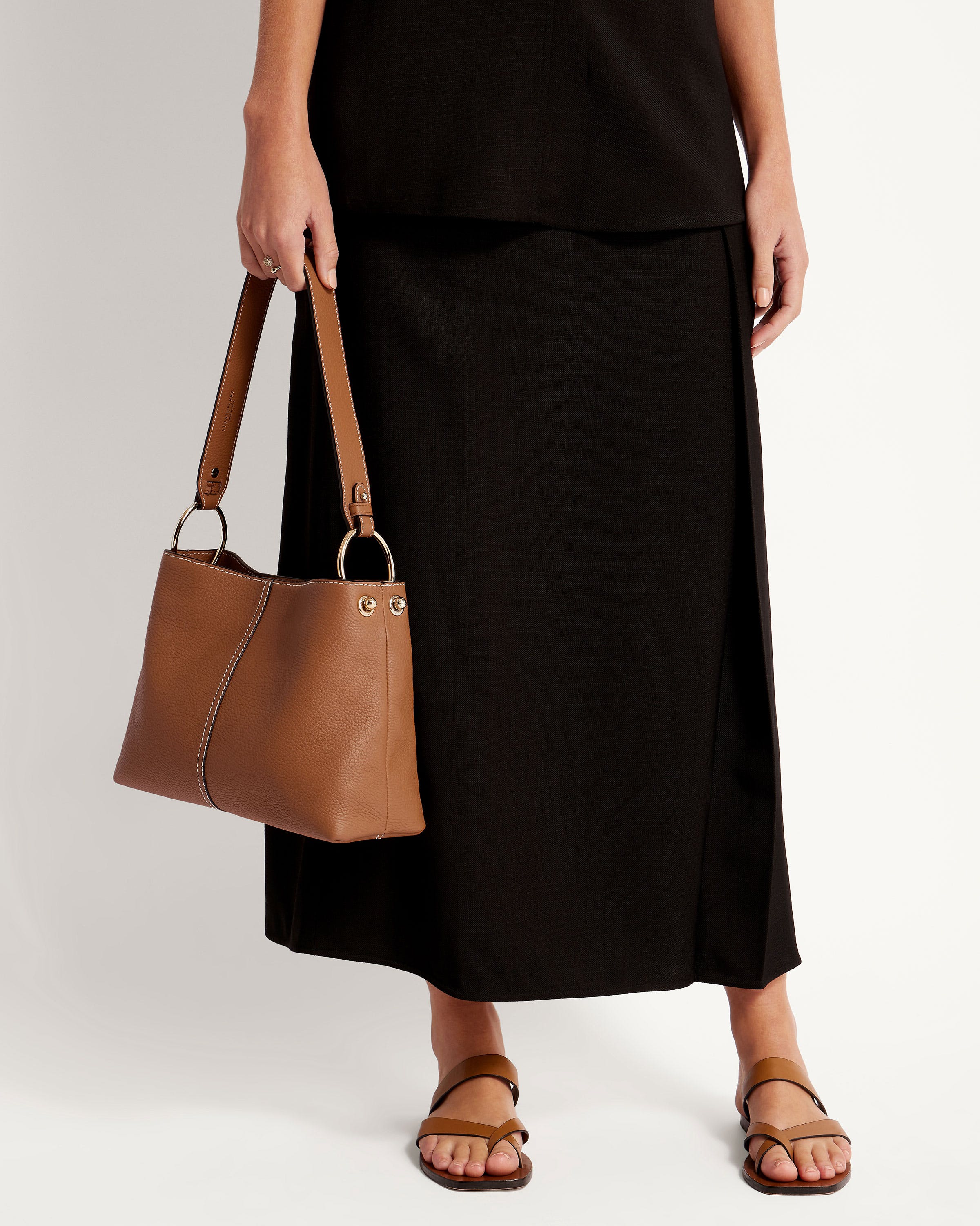 A woman in a black dress holding a brown purse