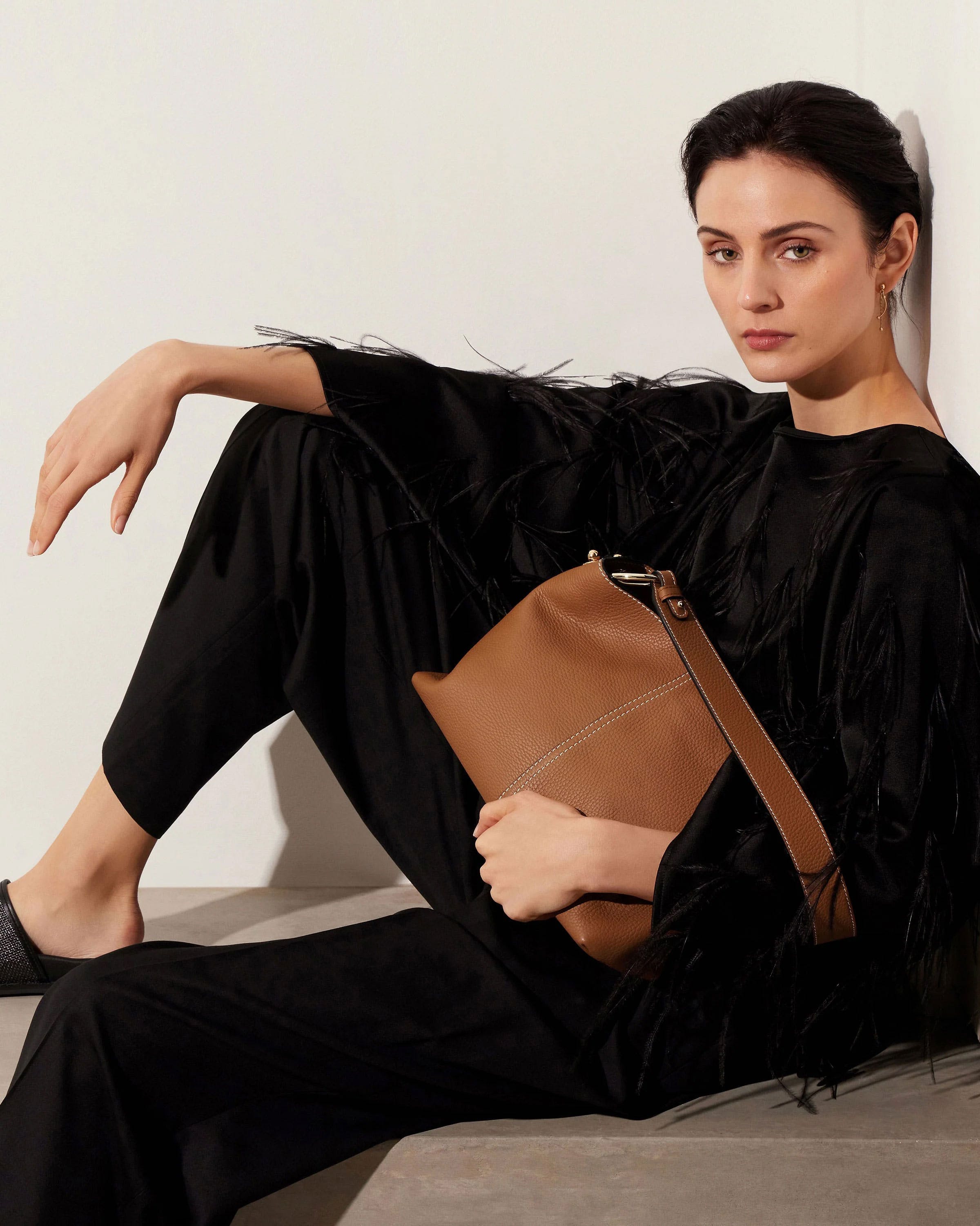 A woman sitting on a ledge holding a brown purse